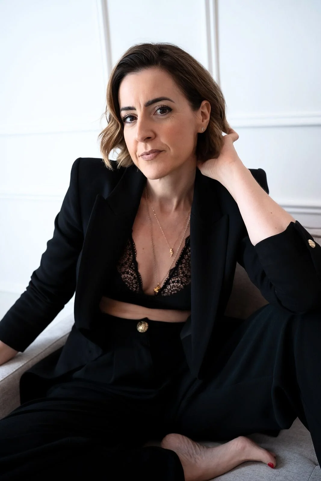 Lisa Moore, Sovereign Frequency Architect, seated in a black suit looking thoughtfully upward, embodying sovereign leadership and presence