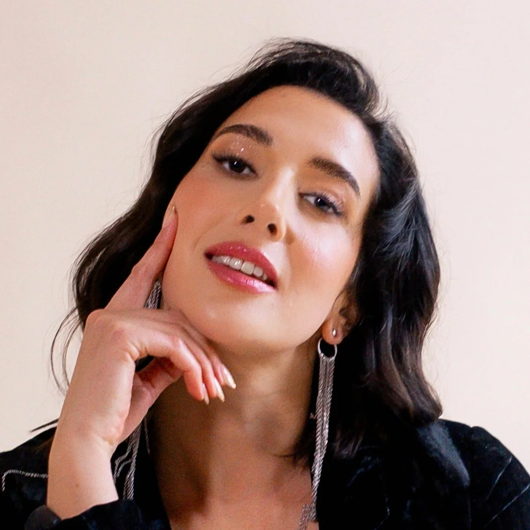 Zahara, client of Lisa Moore, Sovereign Frequency Architect, looking upward with a contemplative expression, wearing silver chain earrings and a black velvet jacket.