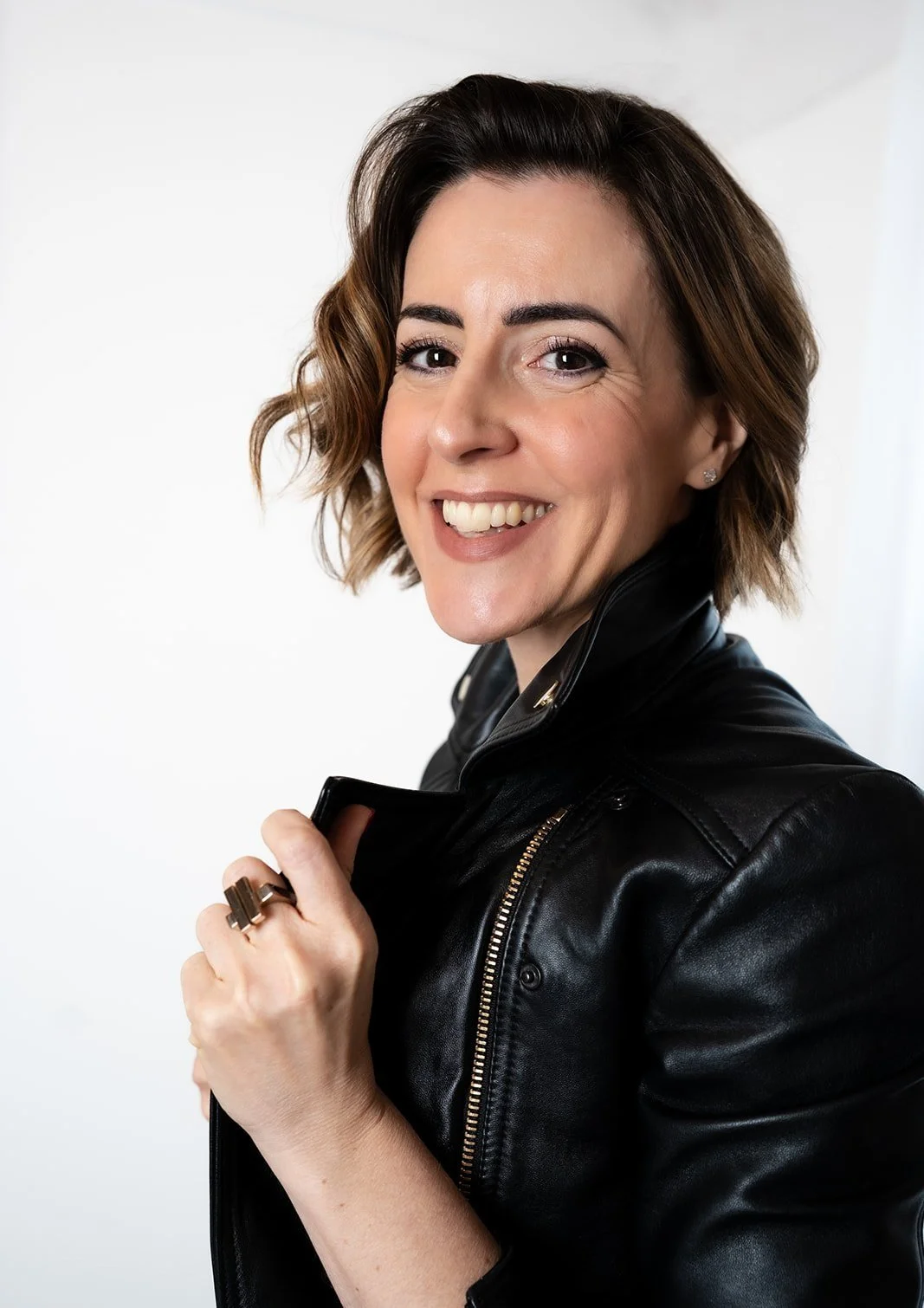 Lisa Moore, founder of House of Soul Sovereignty, holding the lapels of her leather jacket smiling