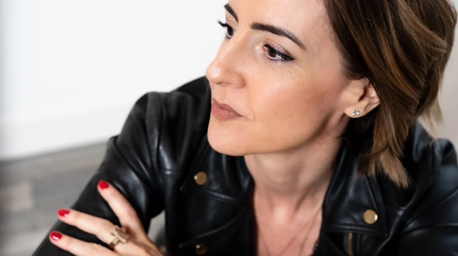 Lisa Moore, Sovereign Frequency Architect and Founder of House of Soul Sovereignty, in side profile looking upward and forward with quiet authority, wearing a black leather jacket with red nails.