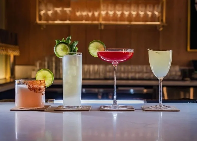 four cocktails on a bartop