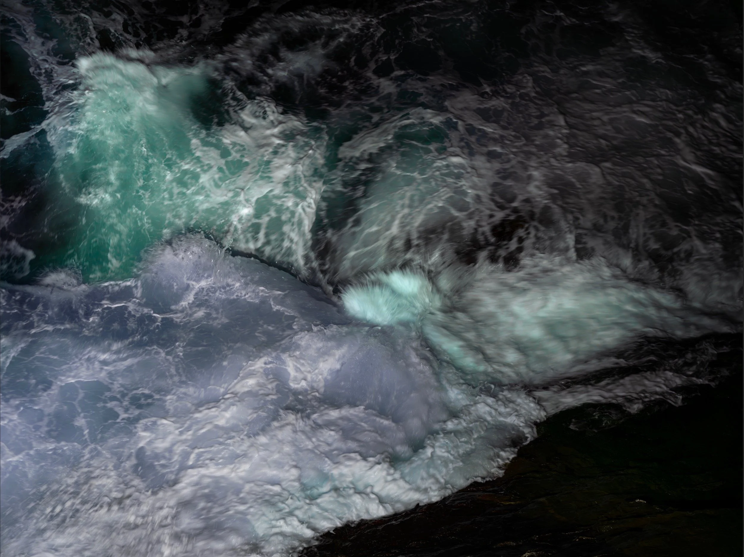 Close-up of turbulent ocean water with white foam and swirling currents.