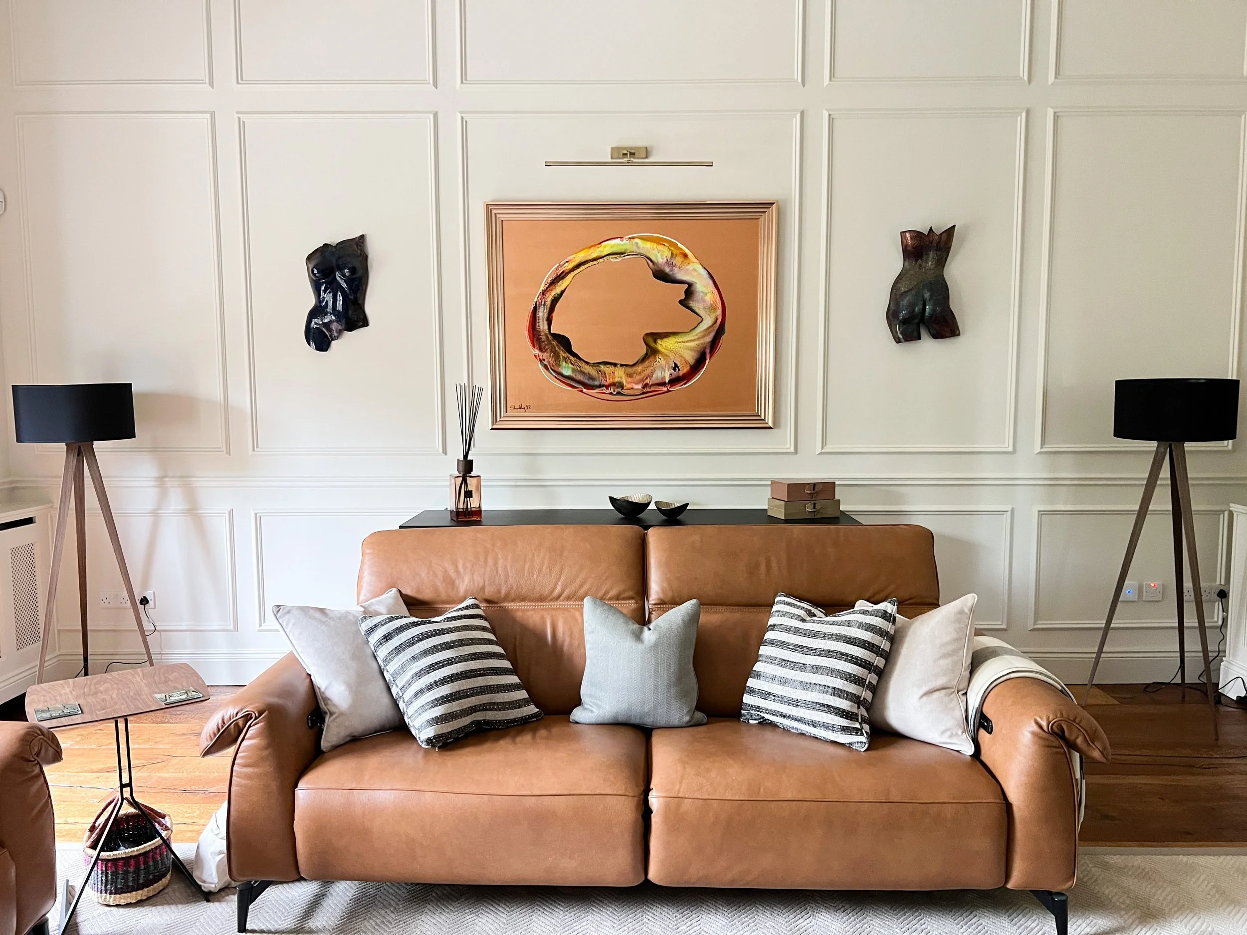 Tan leather sofa set against striking wall panelling and custom artwork