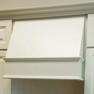White kitchen cabinet with a custom wood hood