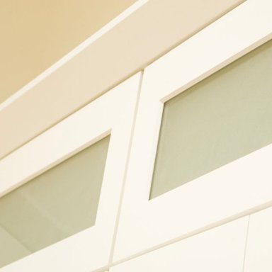 Close-up of a white framed window on a beige exterior wall.