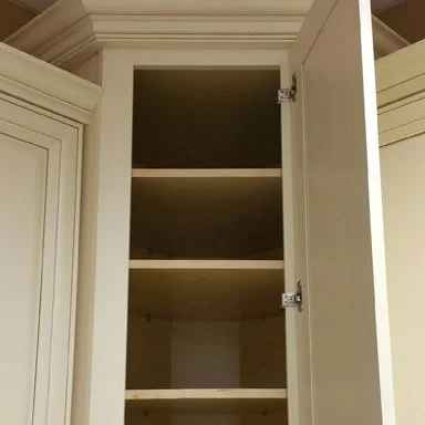 Open white cabinet door showing empty shelves inside.