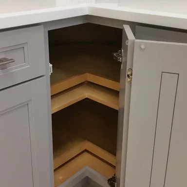 Open corner kitchen cabinet with three wooden shelves inside.