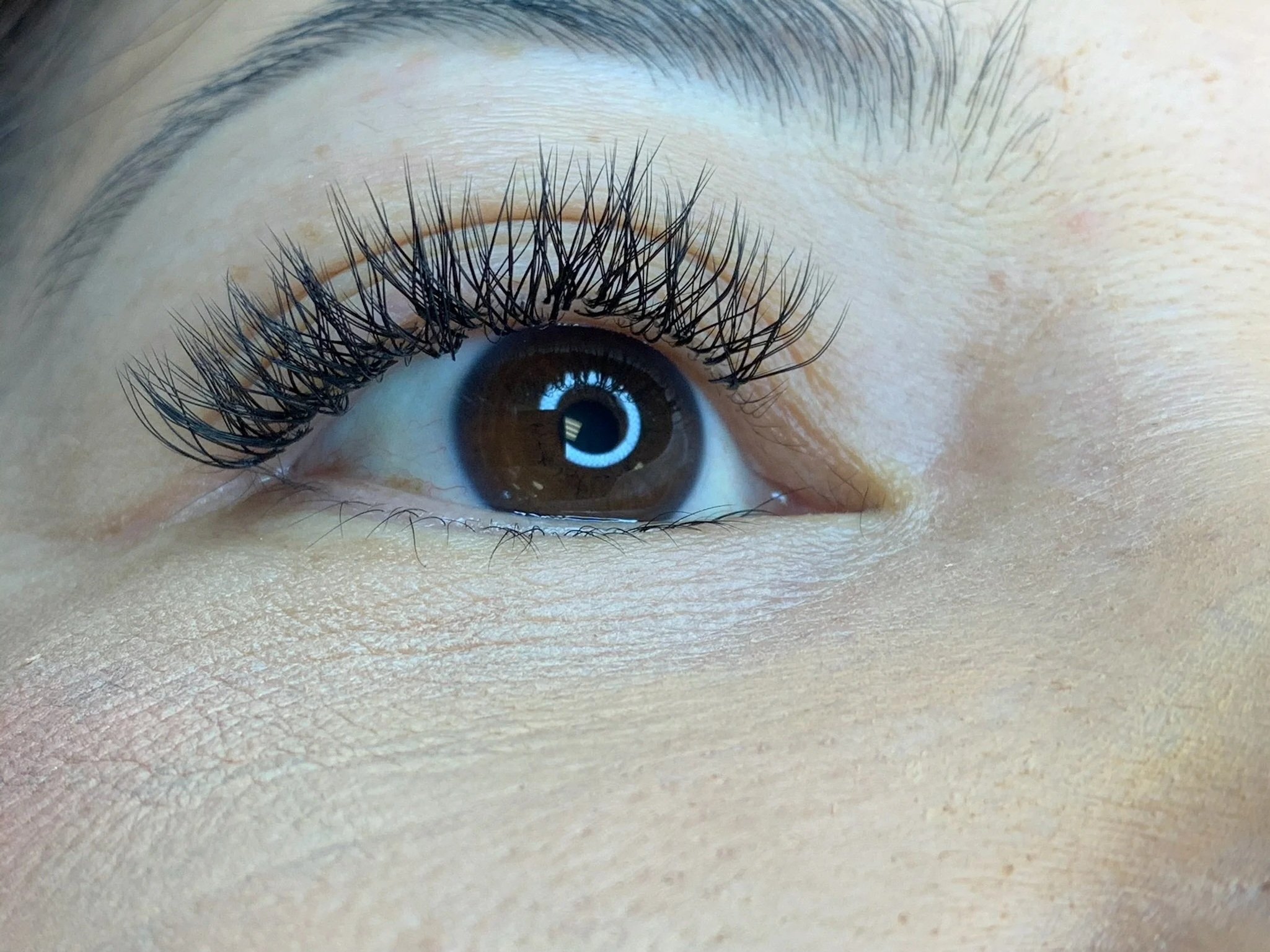 Close-up of a human eye with long, curled eyelashes and brown iris.