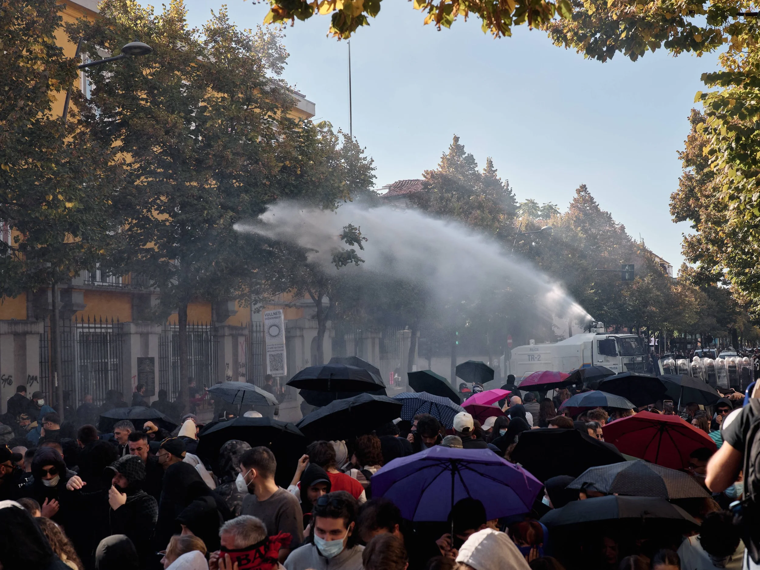Police use water cannons to disperse demonstrators outside the Ministry of Education as students open umbrellas to protect themselves from the water.