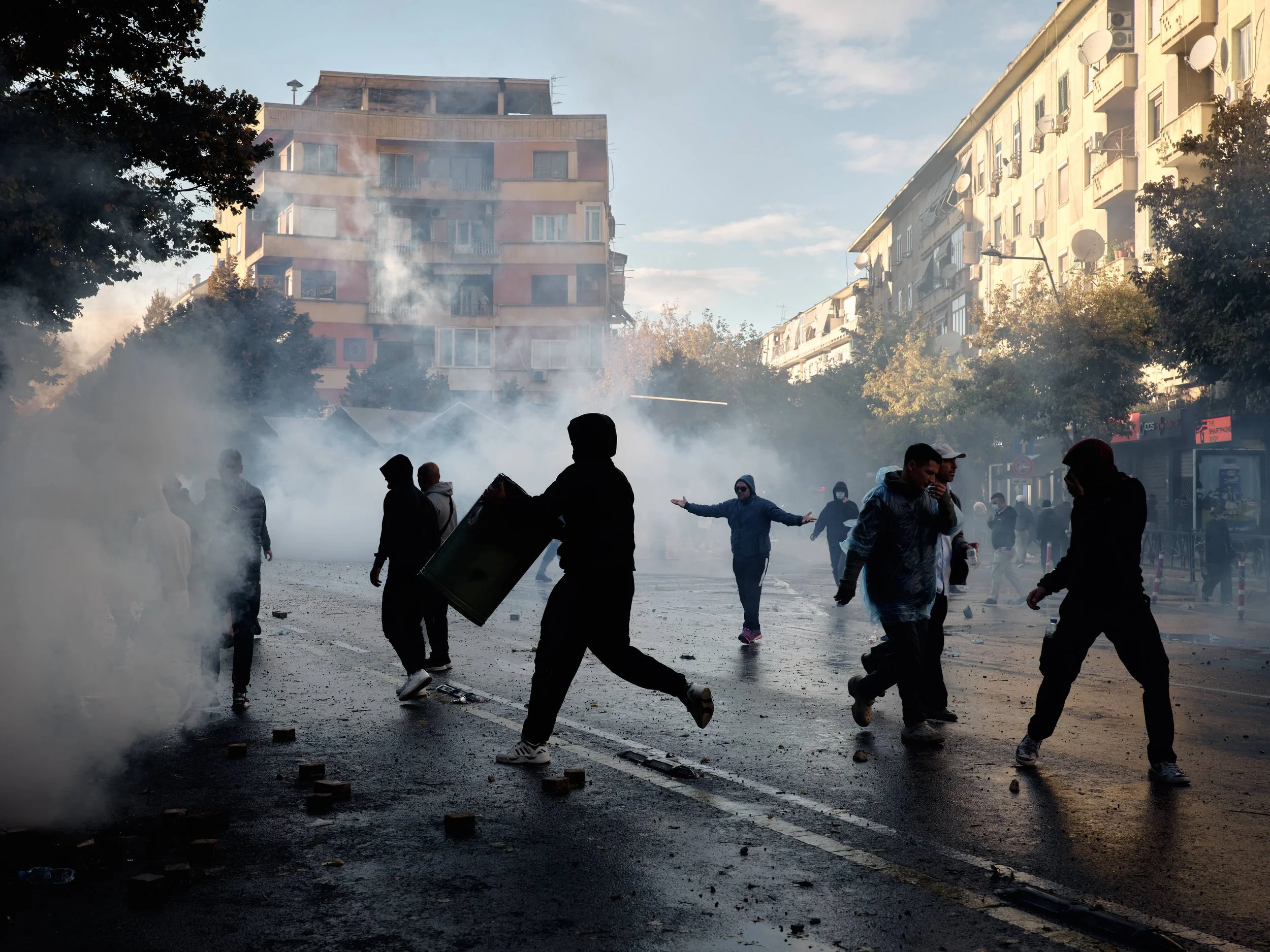 Demonstrators confront tear gas as they use rubbish bins to contain or isolate the gas.