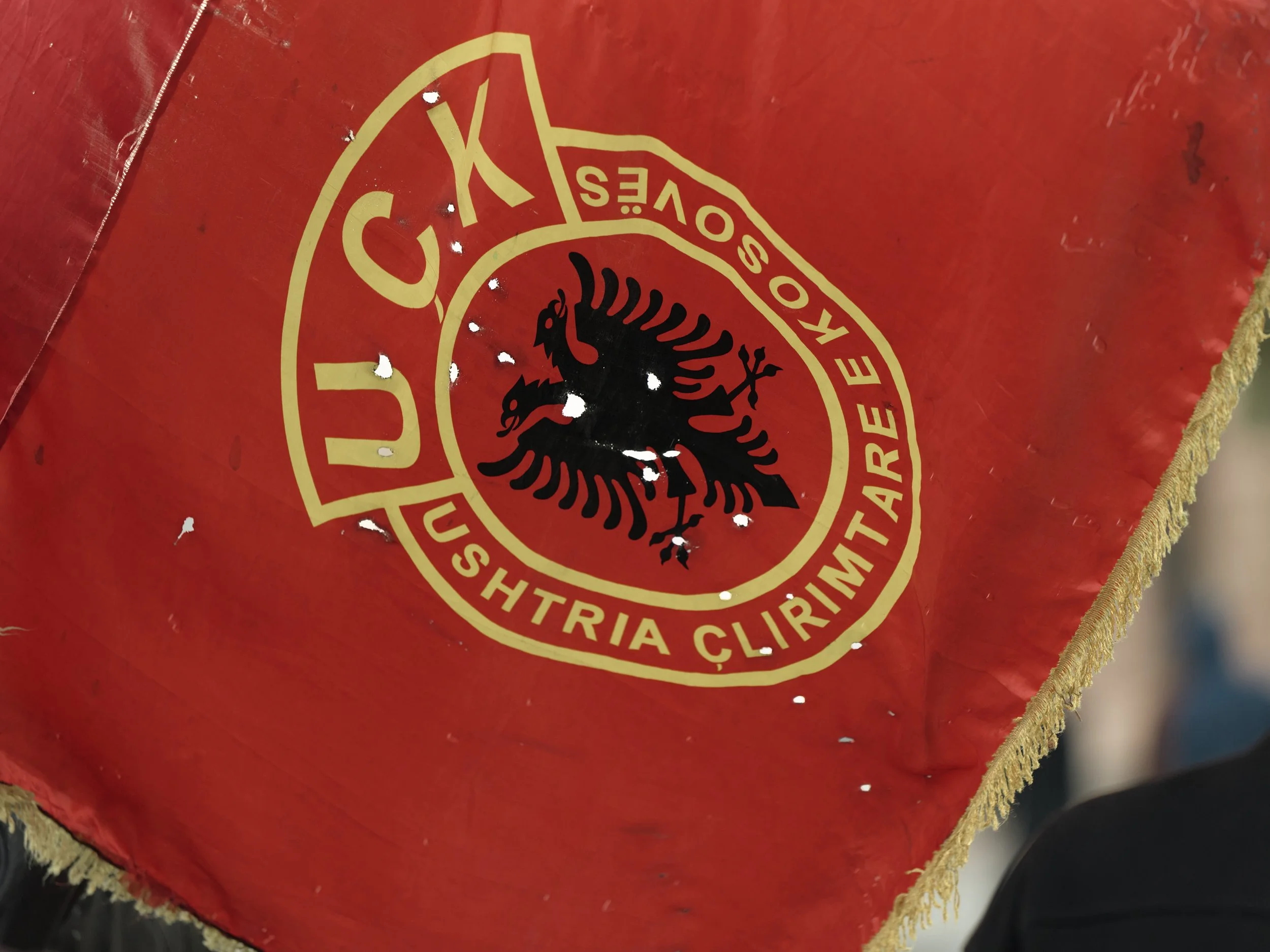 A detail of a Kosovo Liberation Army (KLA/UÇK) flag, riddled with holes and damaged during the protests.