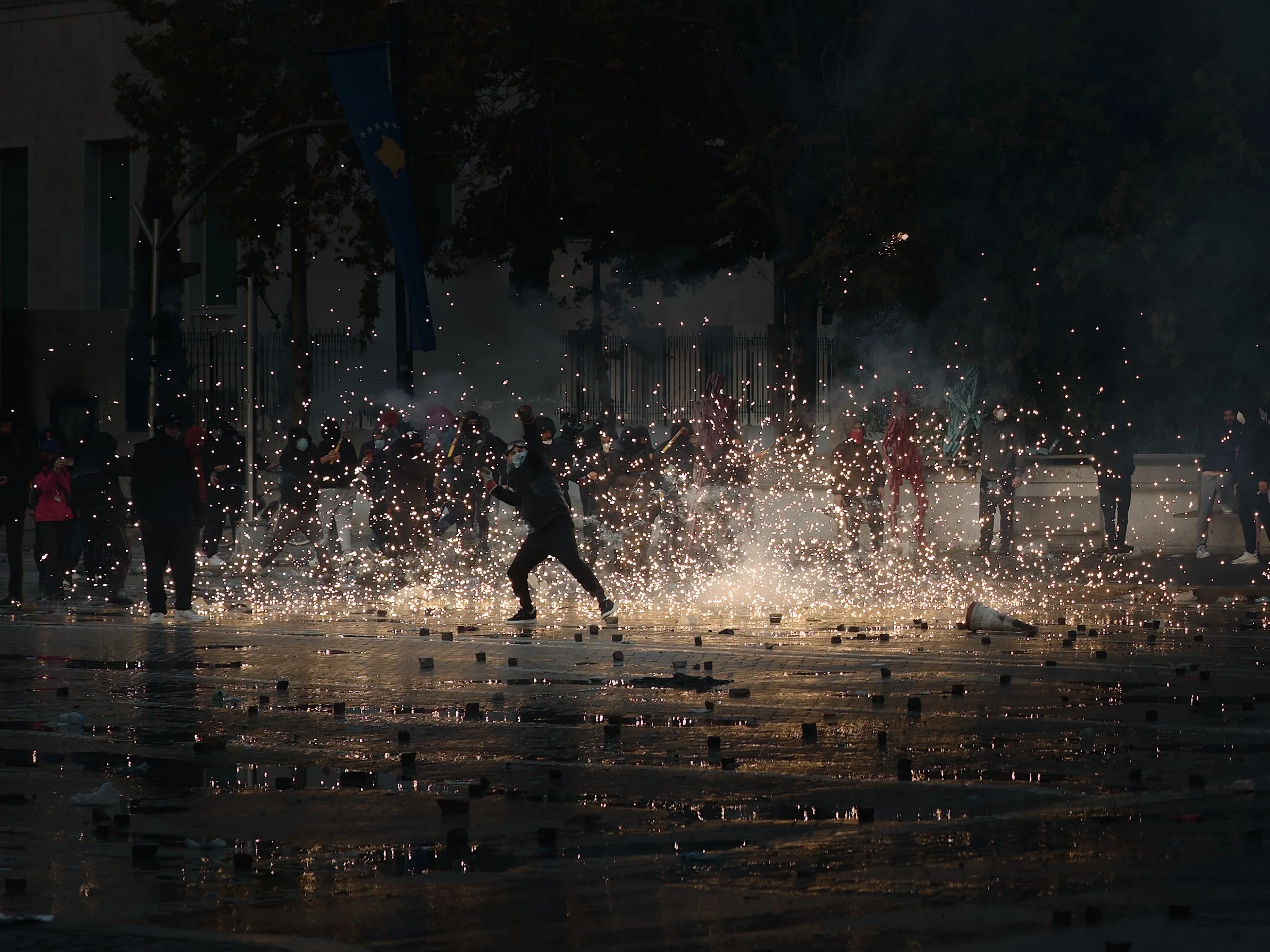 A student throws stones amid fireworks during clashes with police.