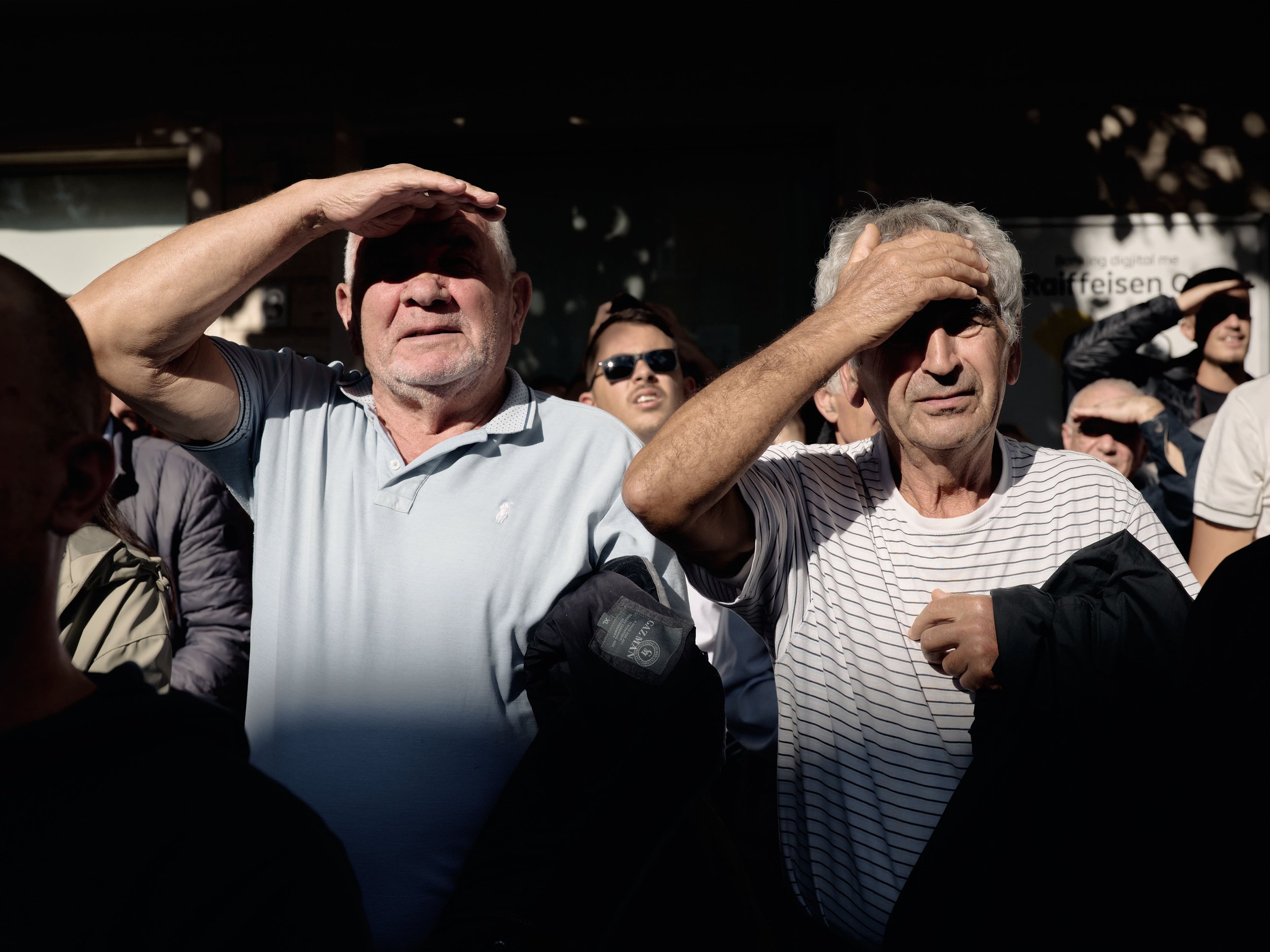 Two men stand as students begin throwing eggs and stones at the Ministry of Education.