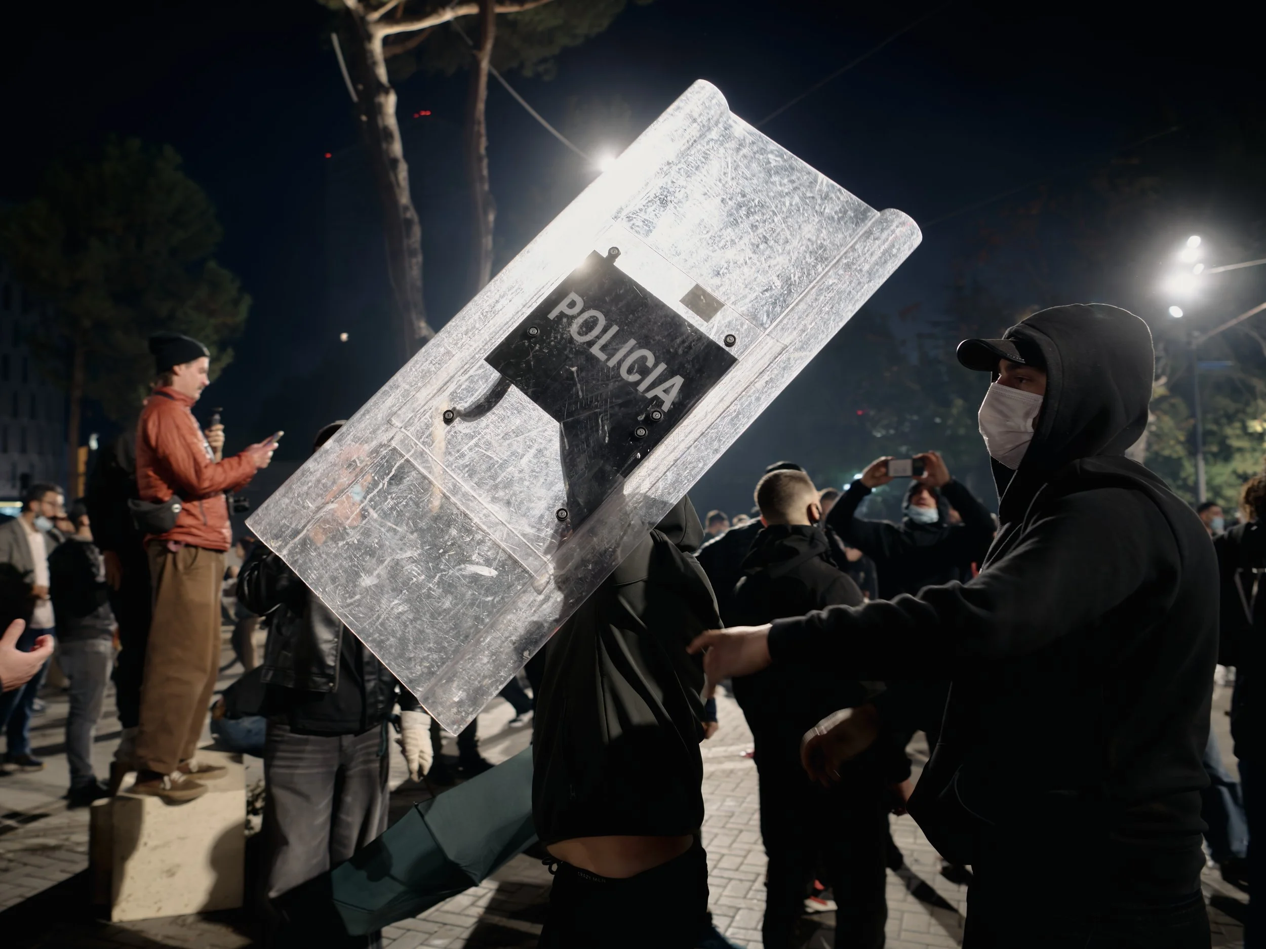 A demonstrator raises a police shield seized from officers in a gesture of celebration.