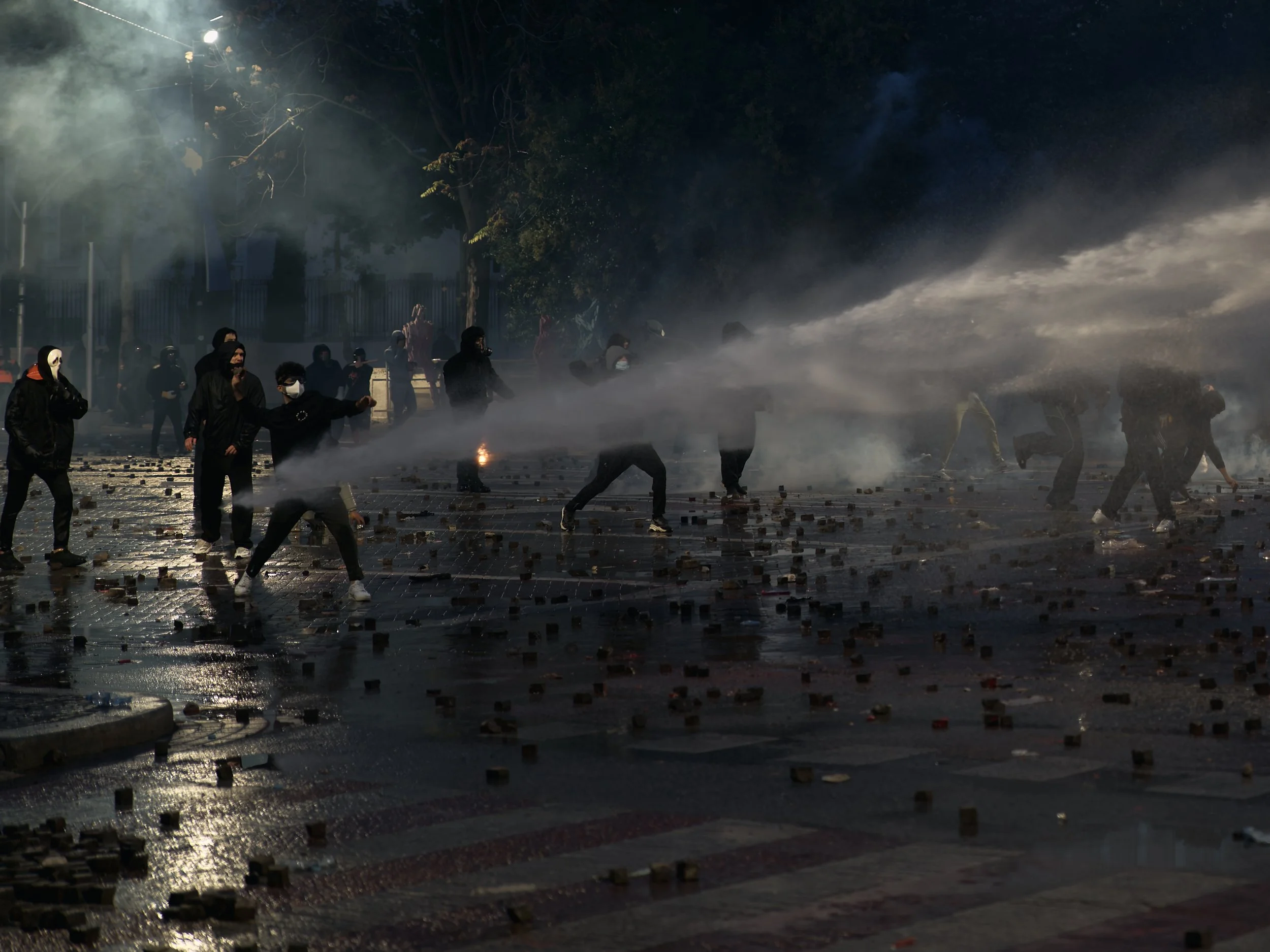 Water from a police cannon strikes demonstrators as they move through the spray along the boulevard.