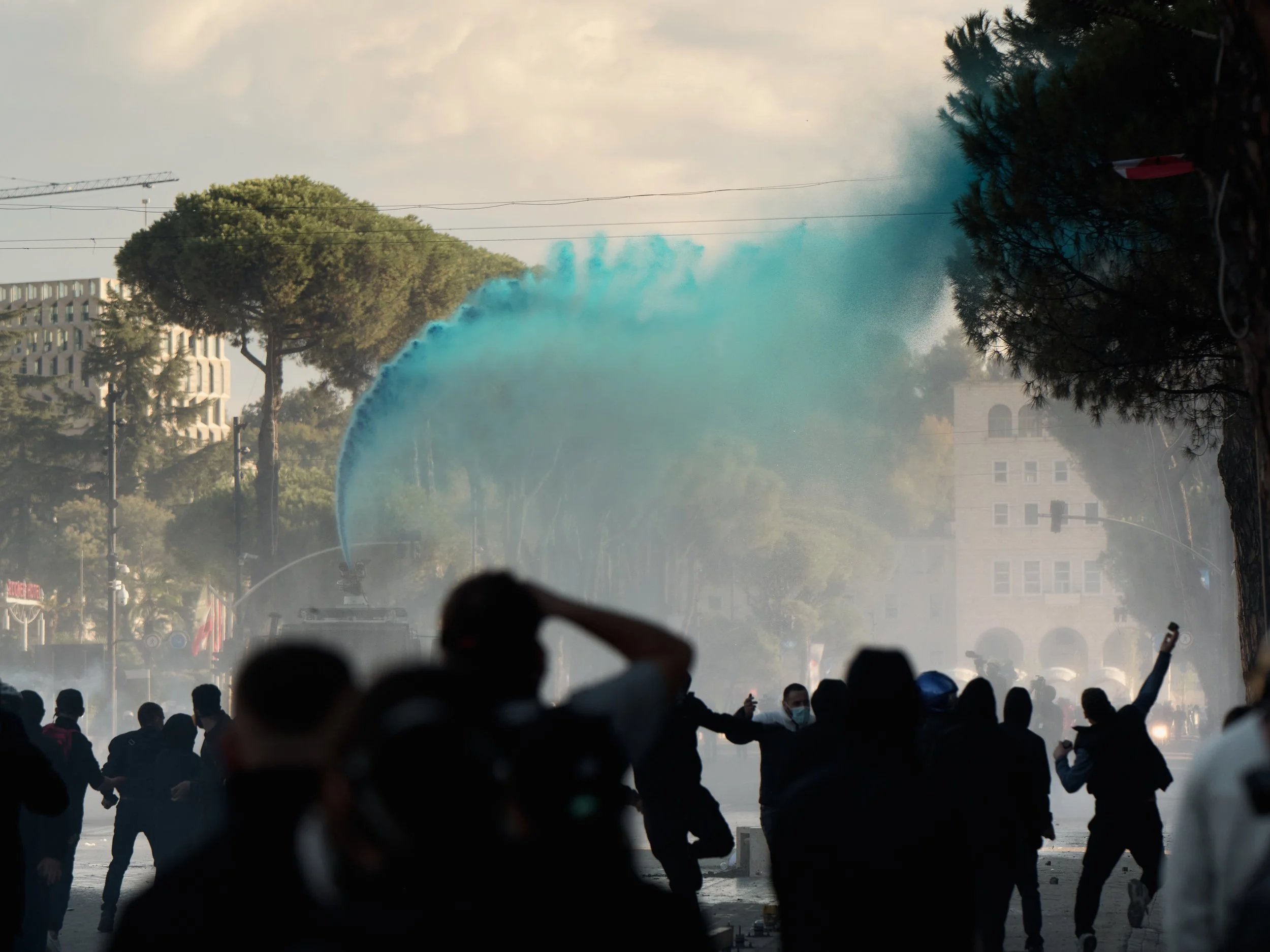 Police fire chemically treated blue water from a water cannon at students along Dëshmorët e Kombit Boulevard in Tirana.