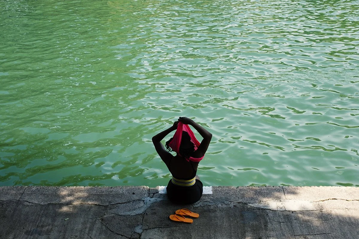 Barton Springs Pool in Austin Texas, woman changing clothes, pink shirt, orange flip flops, colorful portrait by travel photographer Toni Smailagic