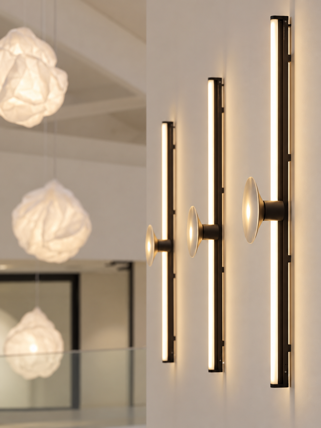 Apliques lineales de pared en tonos cálidos junto a lámparas de papel plegado — solución de iluminación ZONA