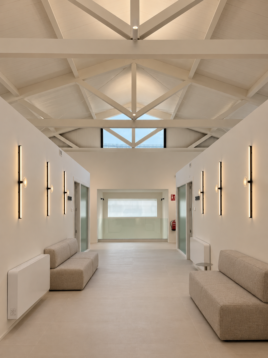 Pasillo con cubierta de madera vista, apliques lineales simétricos en ambas paredes y bancos tapizados — solución de iluminación ZONA