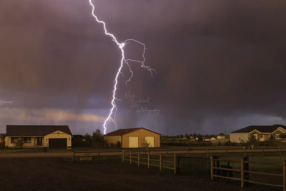 Cheyenne, Wyoming, a late afternoon thunderstorm moving over a residential neighborhood with a lightning strike