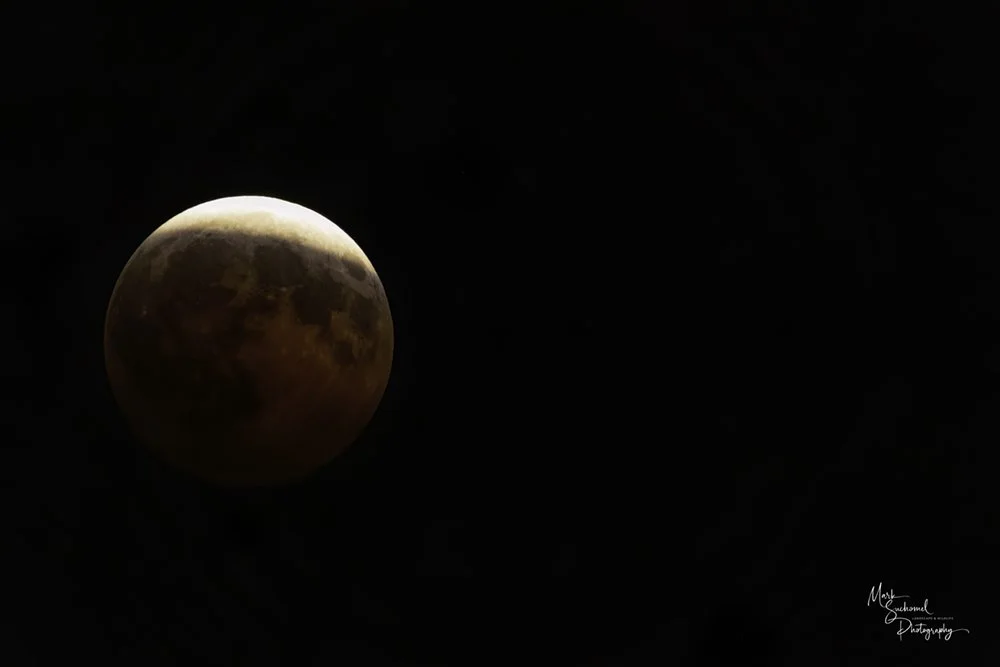 A photo of a blood moon against a night sky as a cloud layer cleared just long enough to make the moon visible.