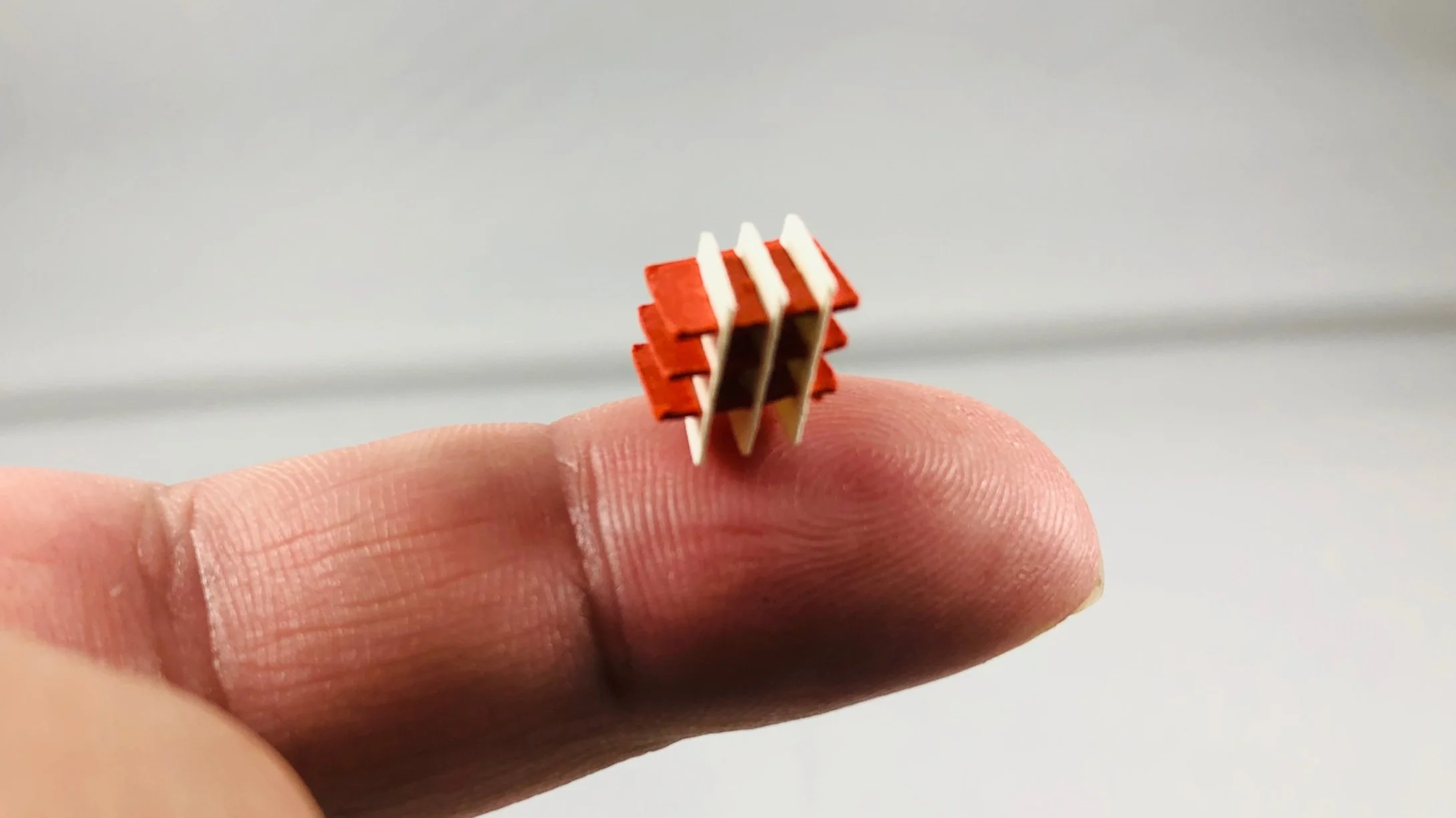 very small woven paper cube pictured on a fingertip for scale