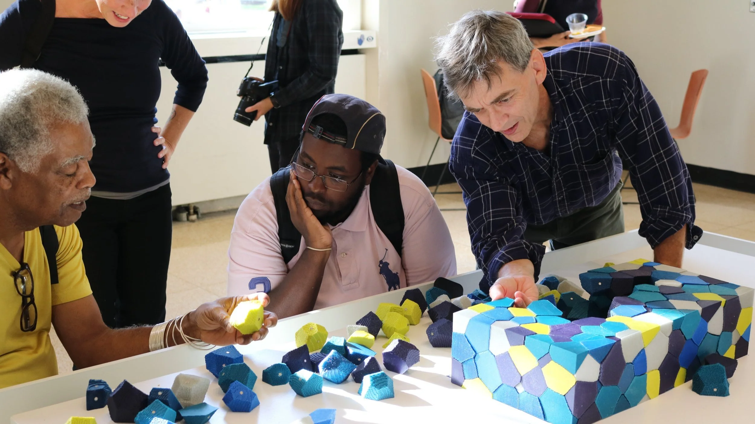 a crowd gathers to investigate a 3d printed puzzle