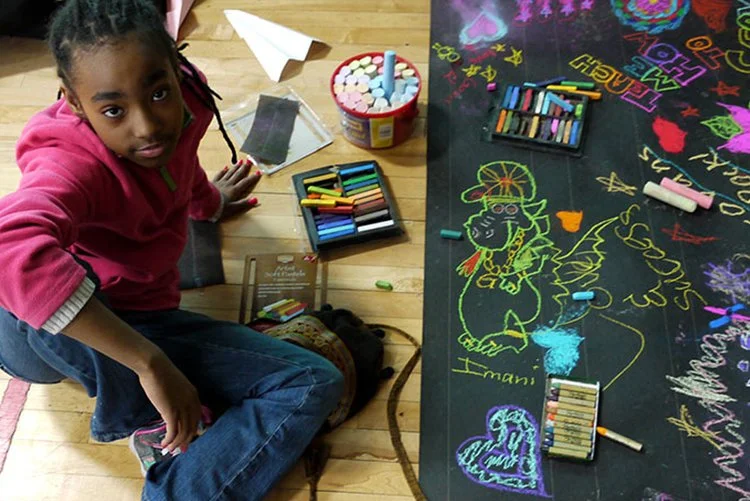 young girl poses in front of chalk based mural