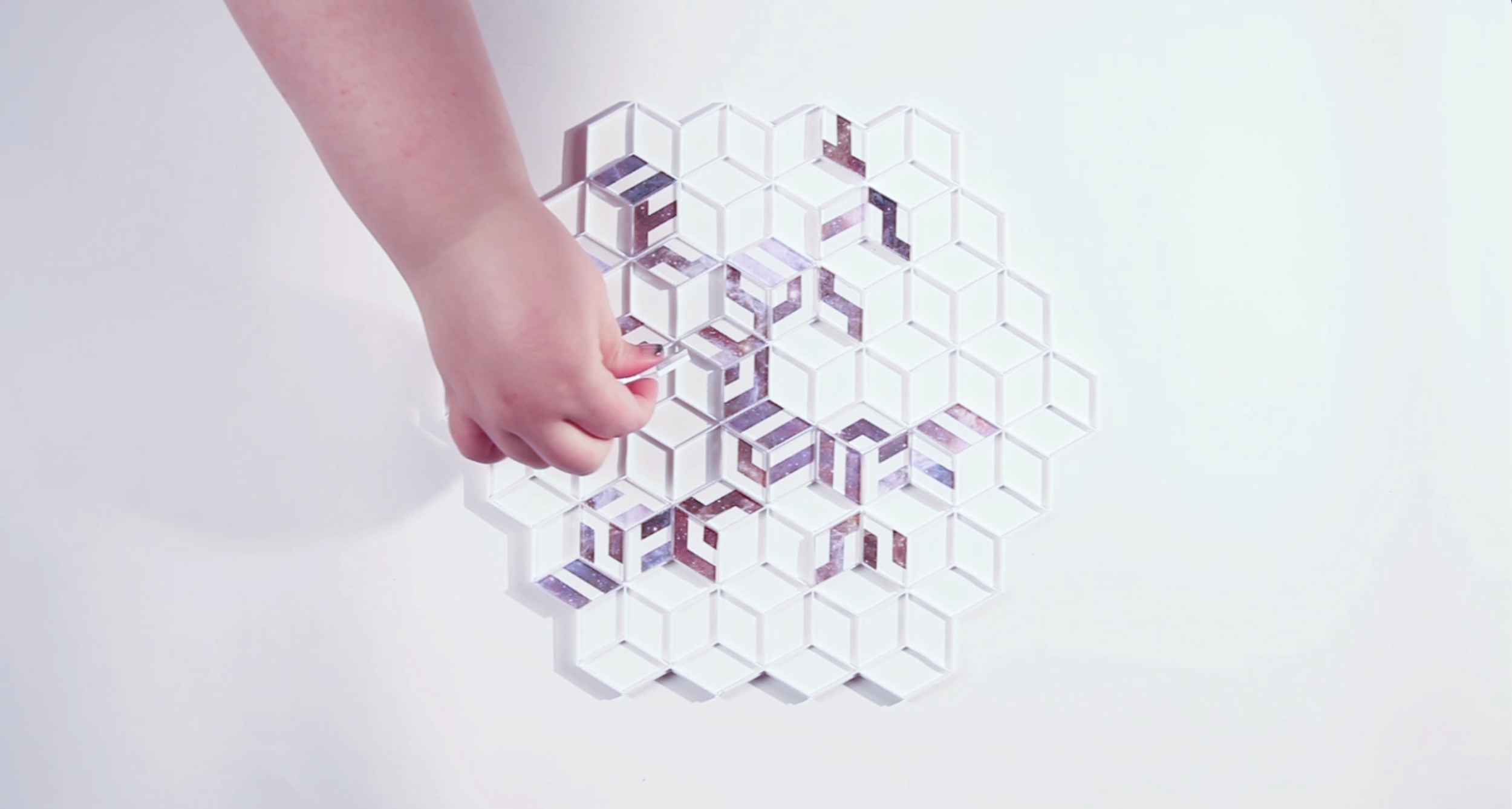 white hand placing purple and white tile on a geometric game board