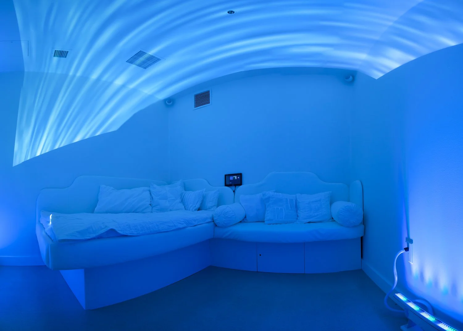 therapeutic water bed and caregiver seating in medical setting under blue water animated lights