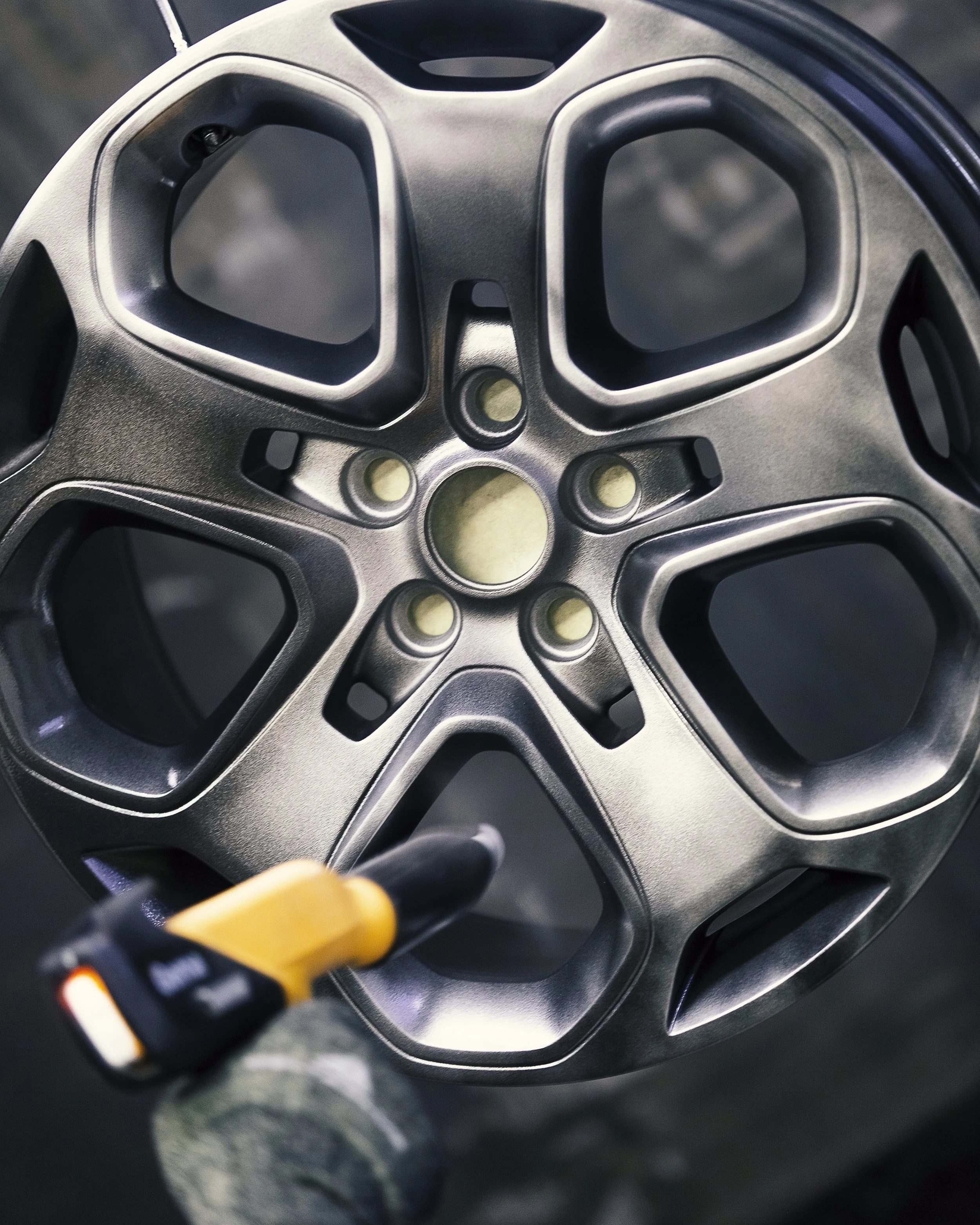 Close-up of a car wheel rim with a person using a tool to work on it.
