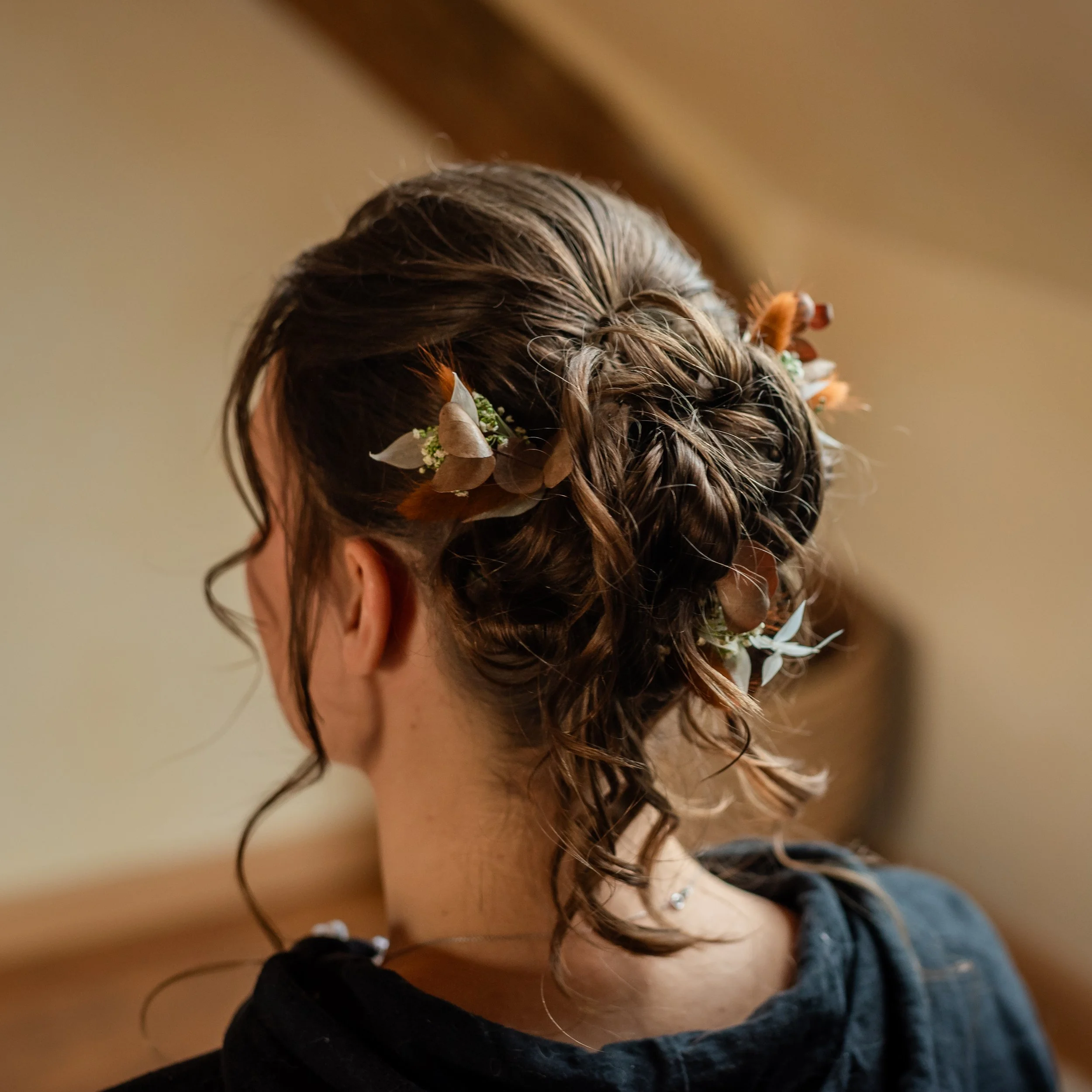 Coiffure avec tresses et fleurs, vue de l'arrière de la tête d'une femme.