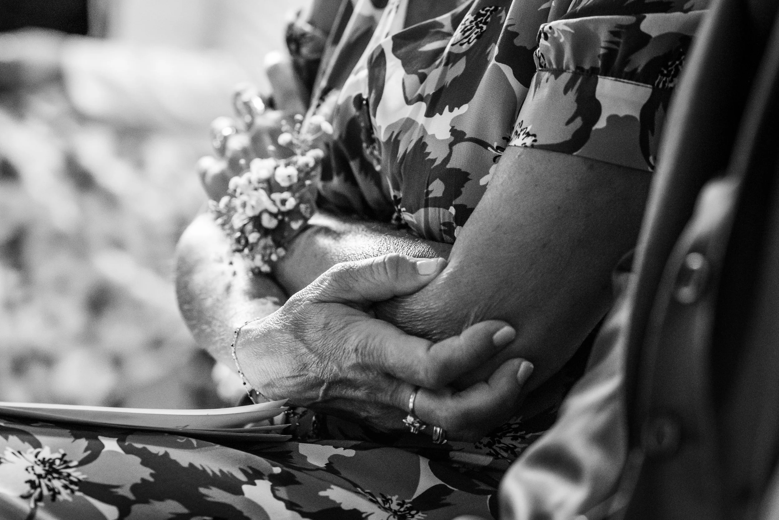 Une personne tient un ange en plastique blanc dans ses mains, assise dans un fauteuil avec un tissu à motif floral.