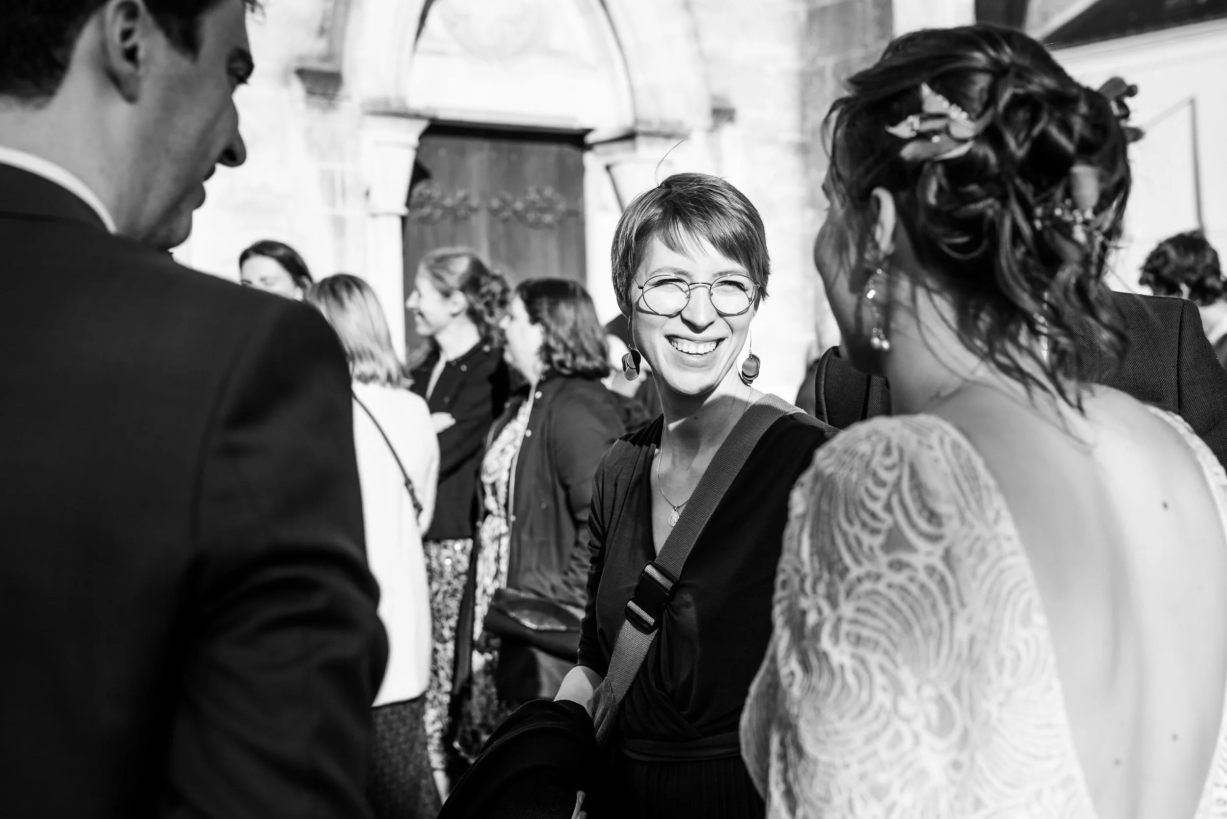 Groupe de personnes en conversation lors d'un événement social en extérieur, en noir et blanc.