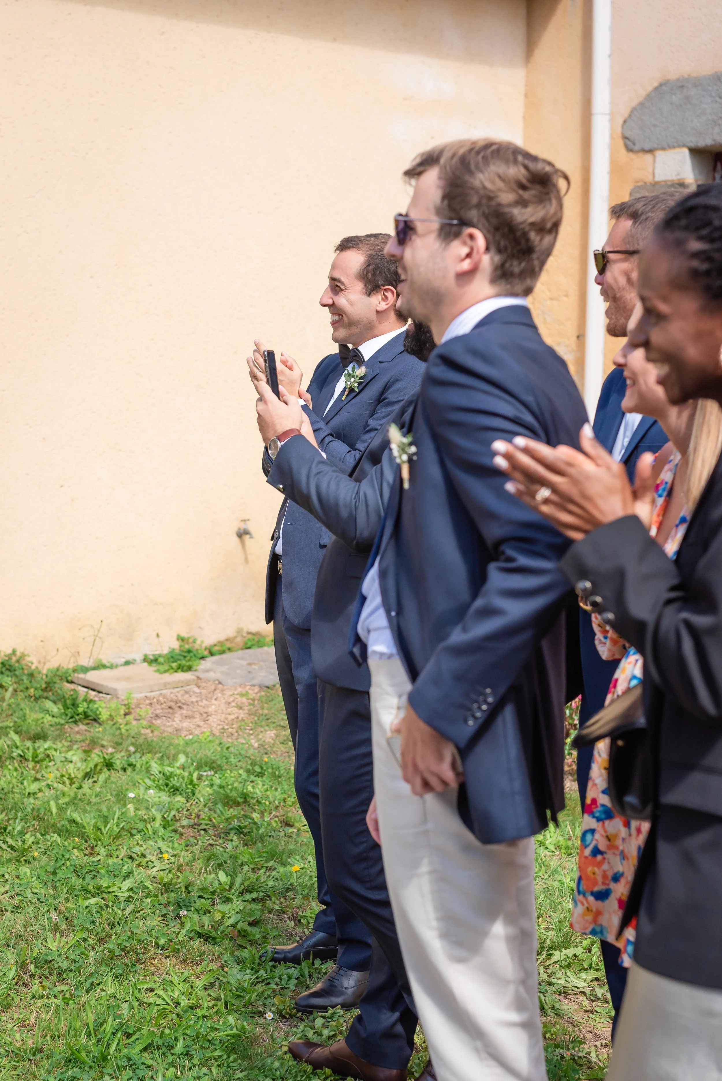 Groupe de personnes habillées en costumes lors d'un événement en extérieur, souriantes et applaudissant.