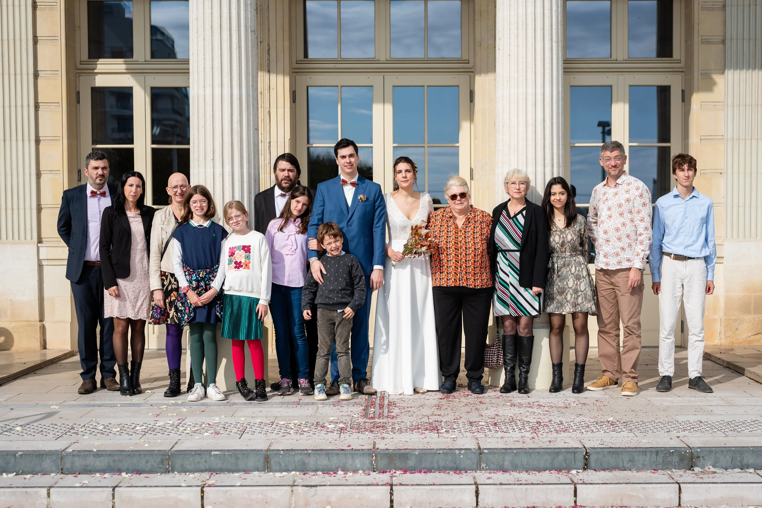 Groupe de personnes posant devant un bâtiment avec des colonnes, occasion spéciale, mariage, famille, cérémonie, cérémonie en plein air.