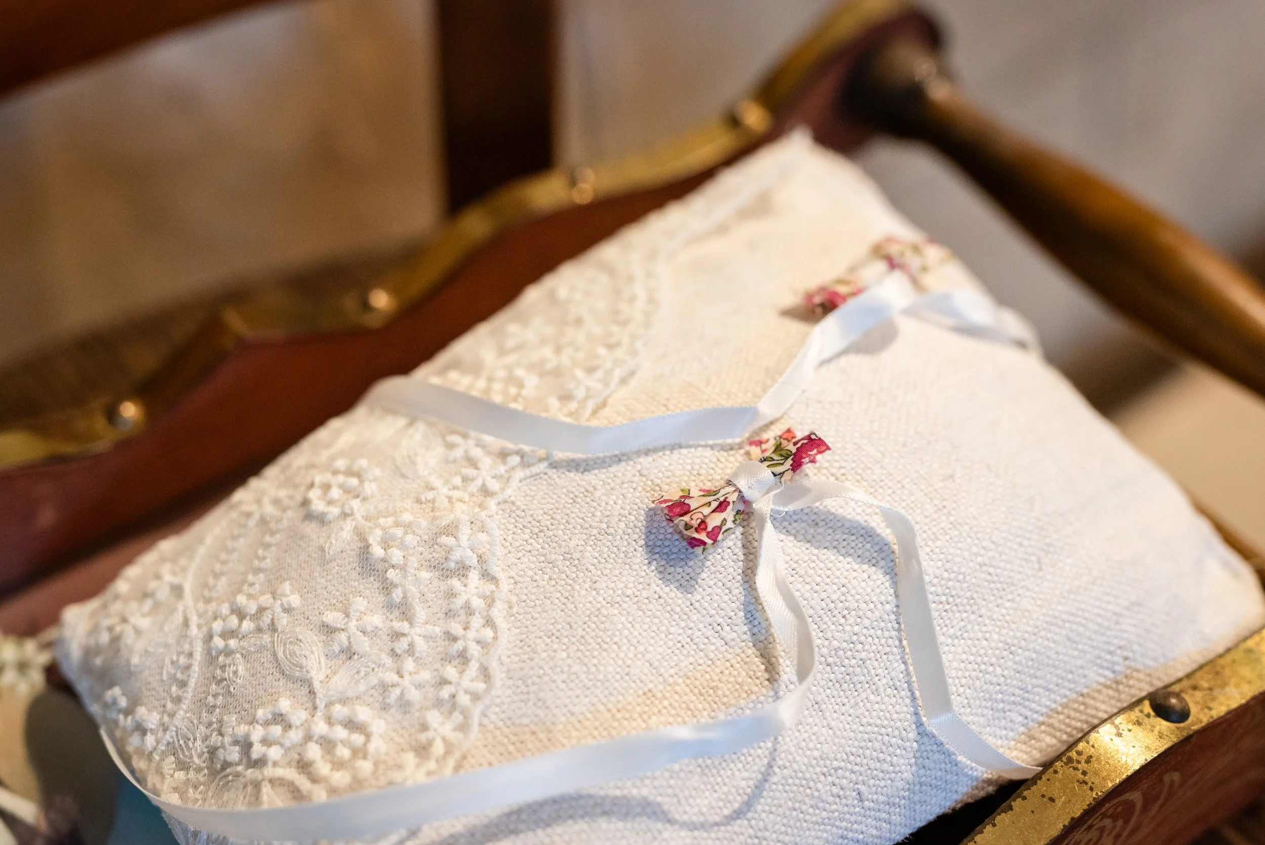 Couverture de livre avec une dentelle blanche, un ruban blanc et des fleurs en tissu, posée sur une surface en bois.
