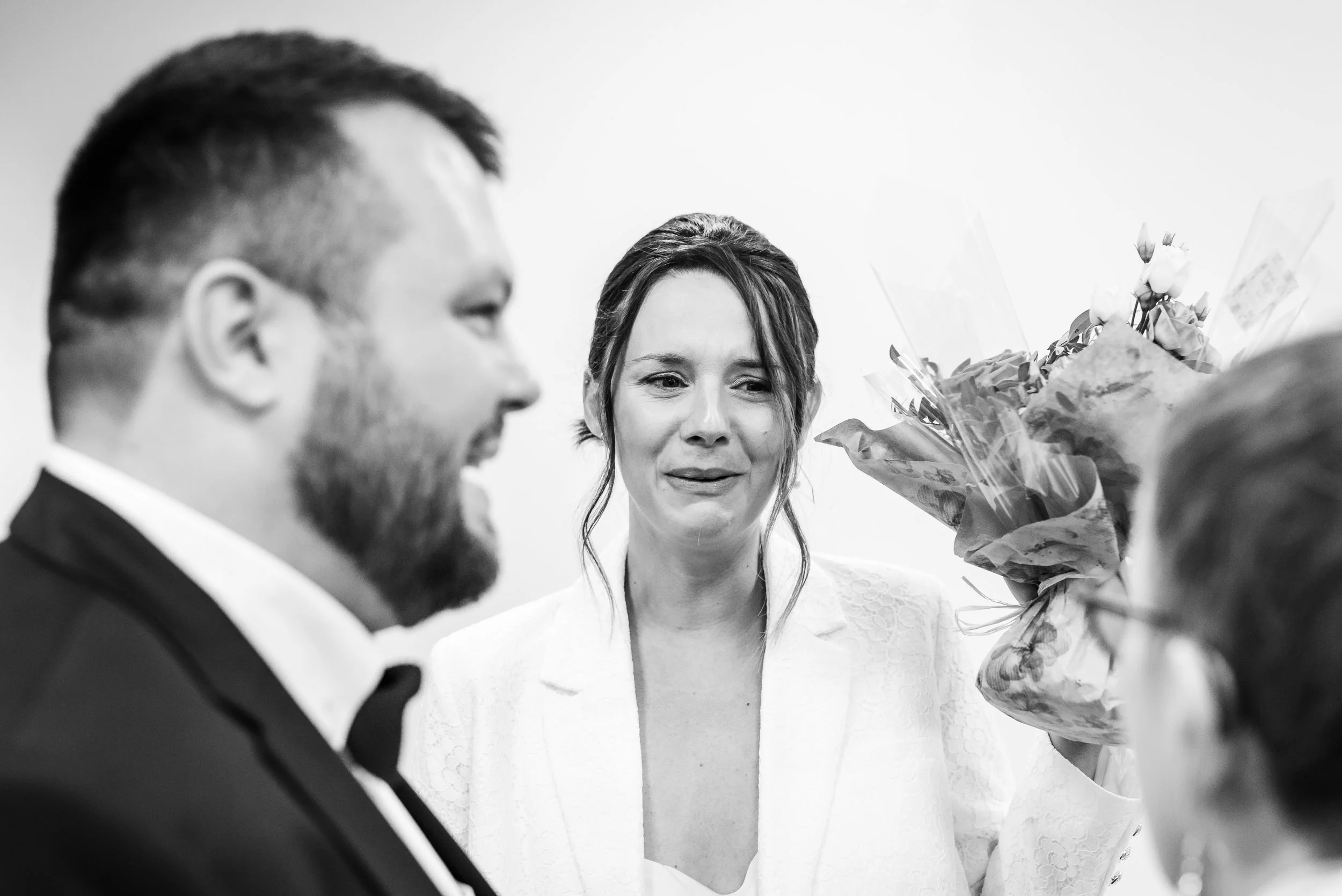 Une femme avec une expression émue reçoit des fleurs d'un autre personne lors d'une cérémonie ou d'une occasion spéciale, dans un environnement intérieur.