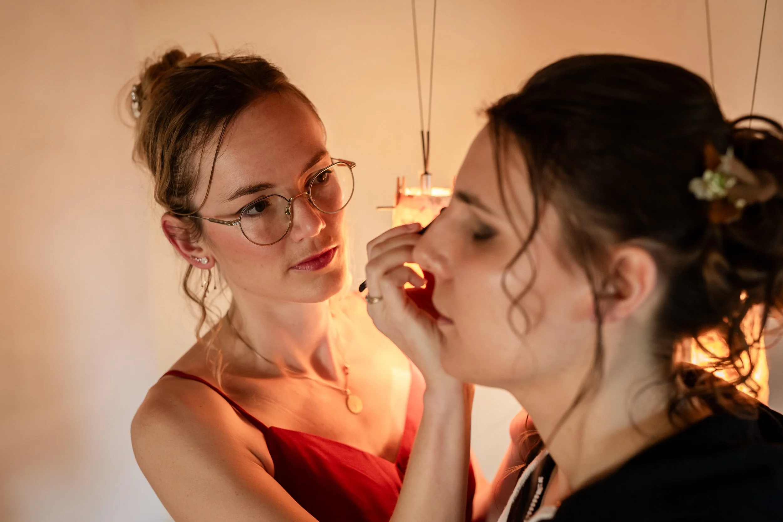 Deux femmes se maquillant mutuellement dans une ambiance chaleureuse et intime.