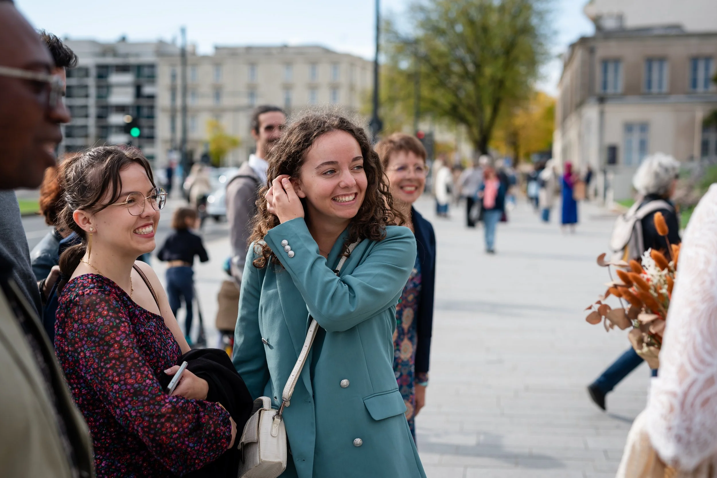 Groupe de personnes souriantes et engagées lors d'une conversation en plein air dans une ville.