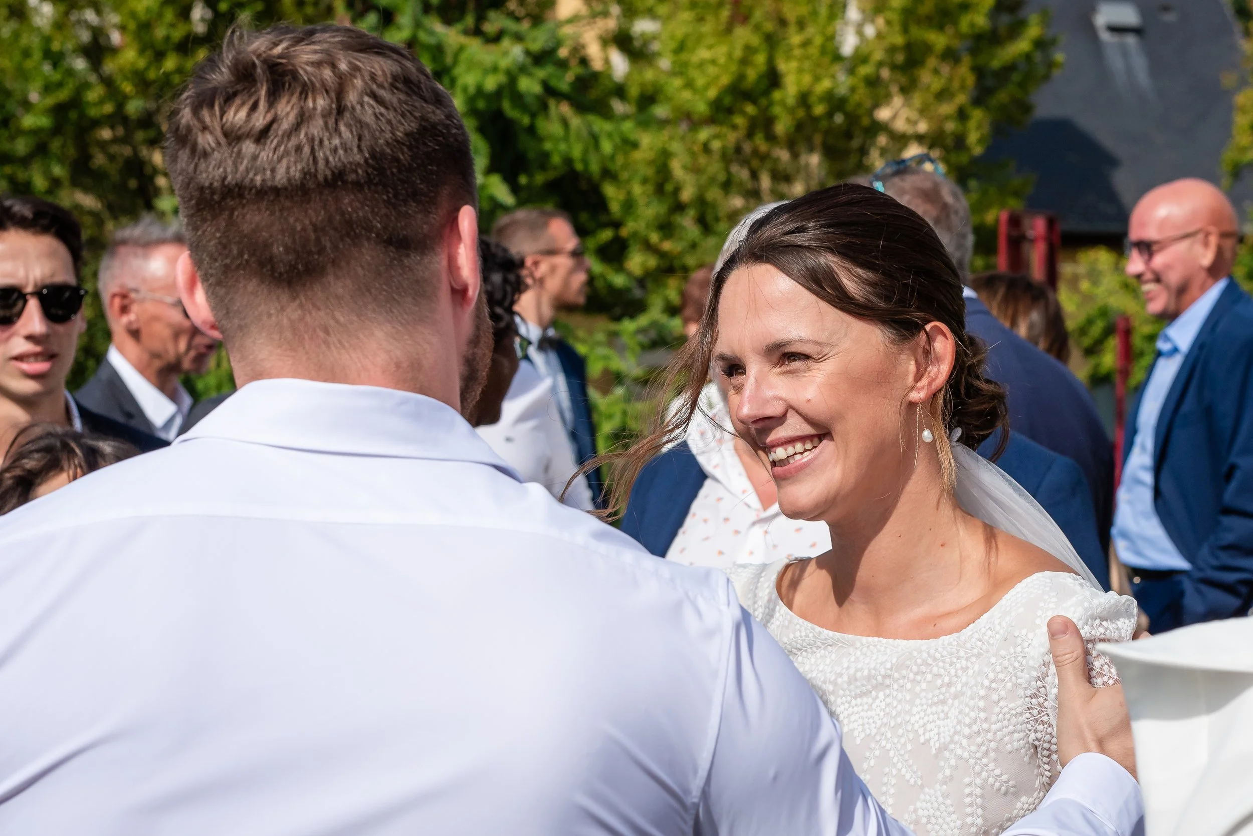 Un couple en tenue de mariage danse lors d'une cérémonie en extérieur, entourés d'invités.