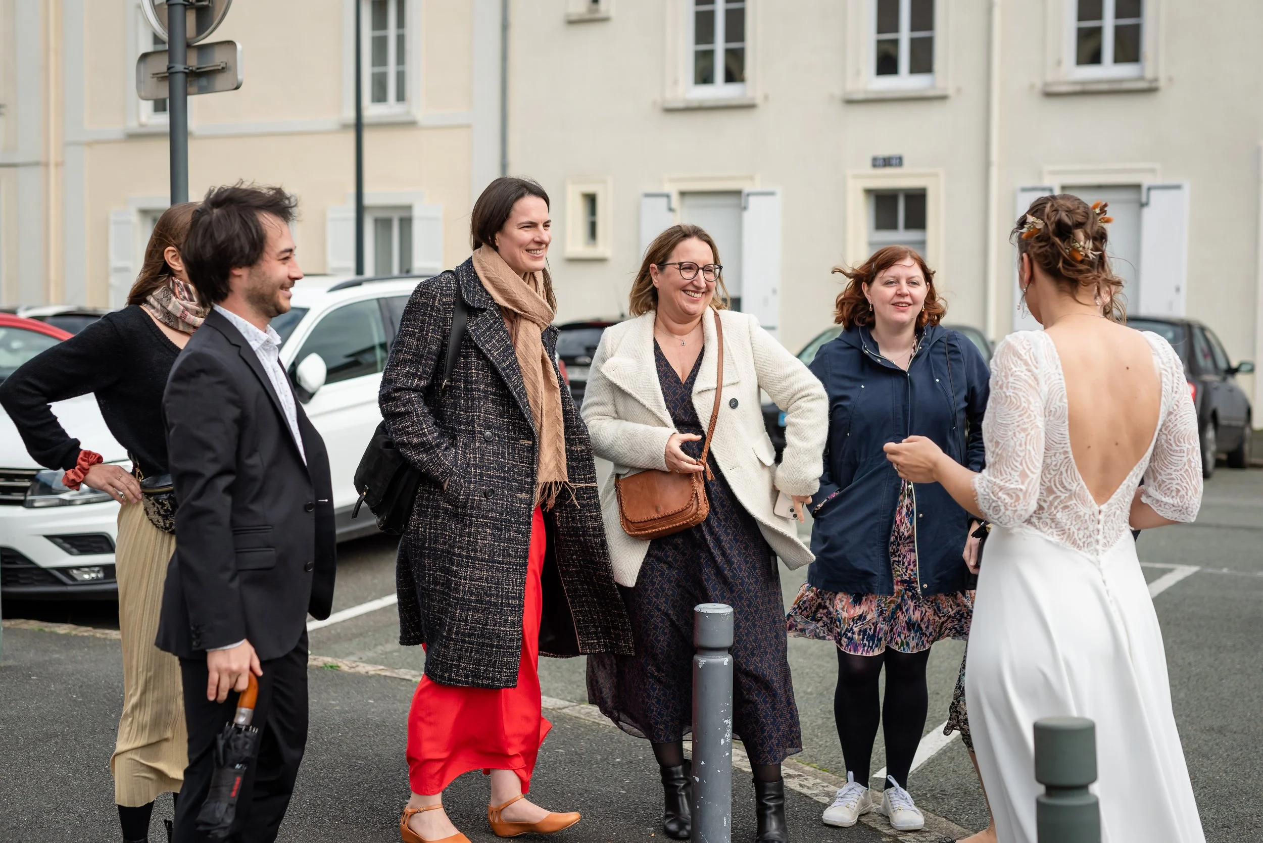 Groupe de personnes discutant dans une rue en France, avec bâtiments résidentiels en arrière-plan, à l'occasion d'une rencontre ou d'une célébration.