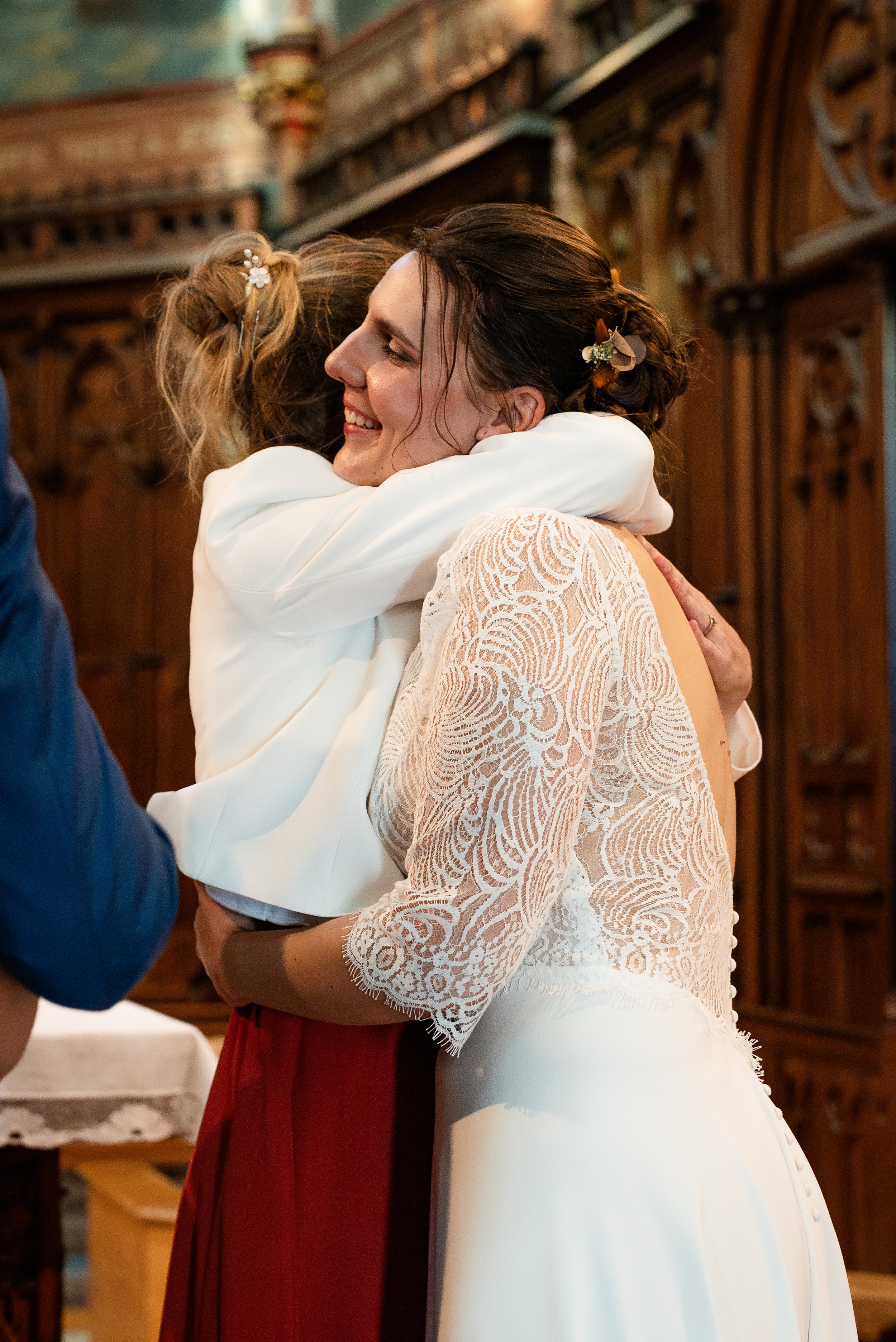 Deux femmes qui s'embrassent en souriant, lors d'une occasion spéciale, dans une salle avec un décor en bois.