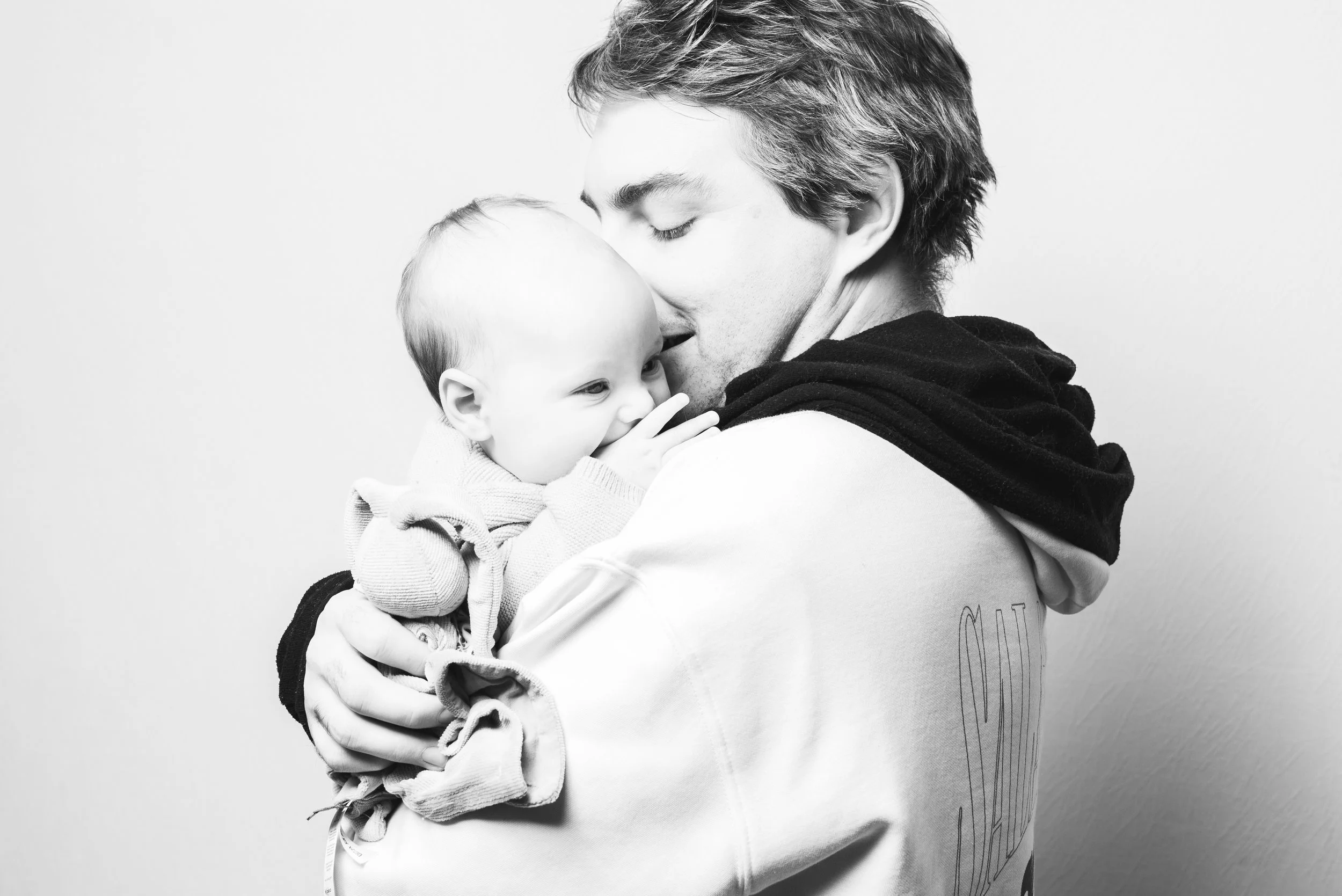 Un homme tient un bébé dans ses bras, ils se regardent tendrement, nuit à une lumière douce.
