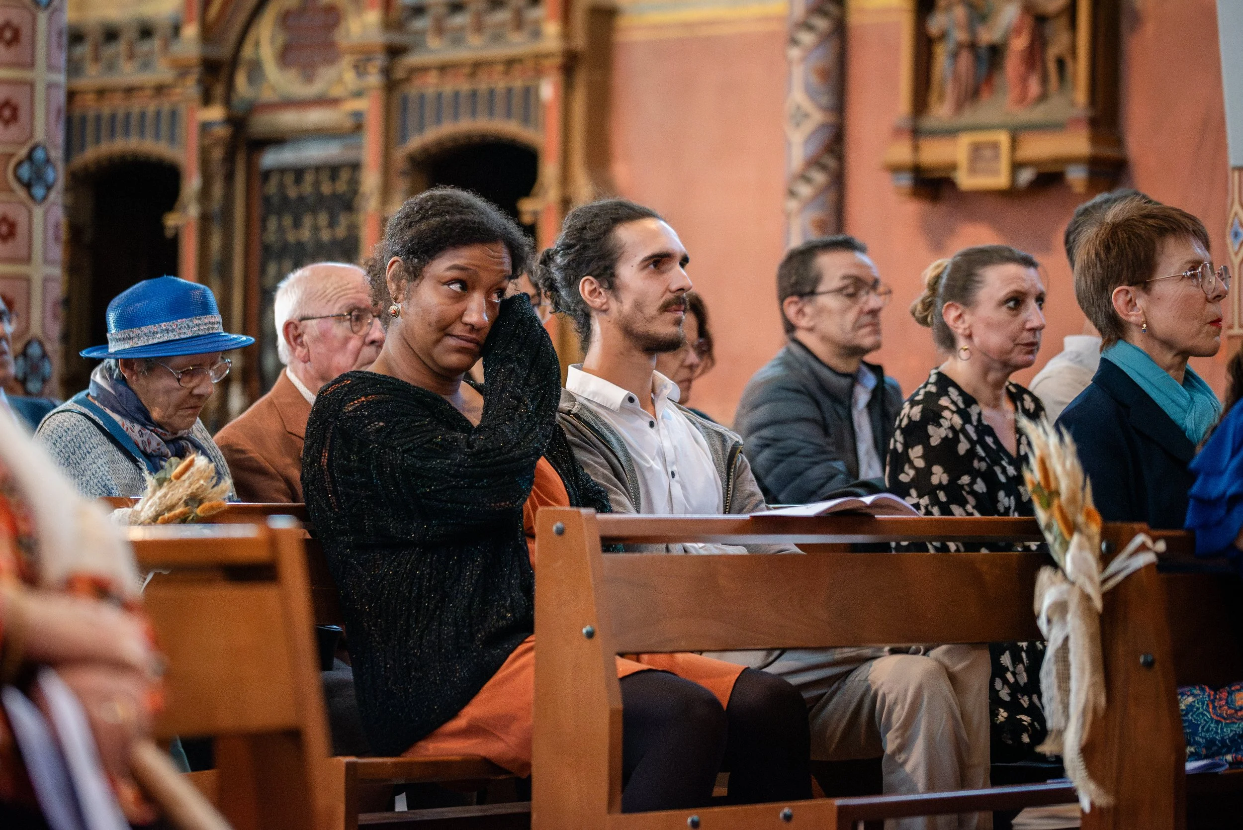 Groupe de personnes assises dans une église, écoutant un service religieux ou une cérémonie.