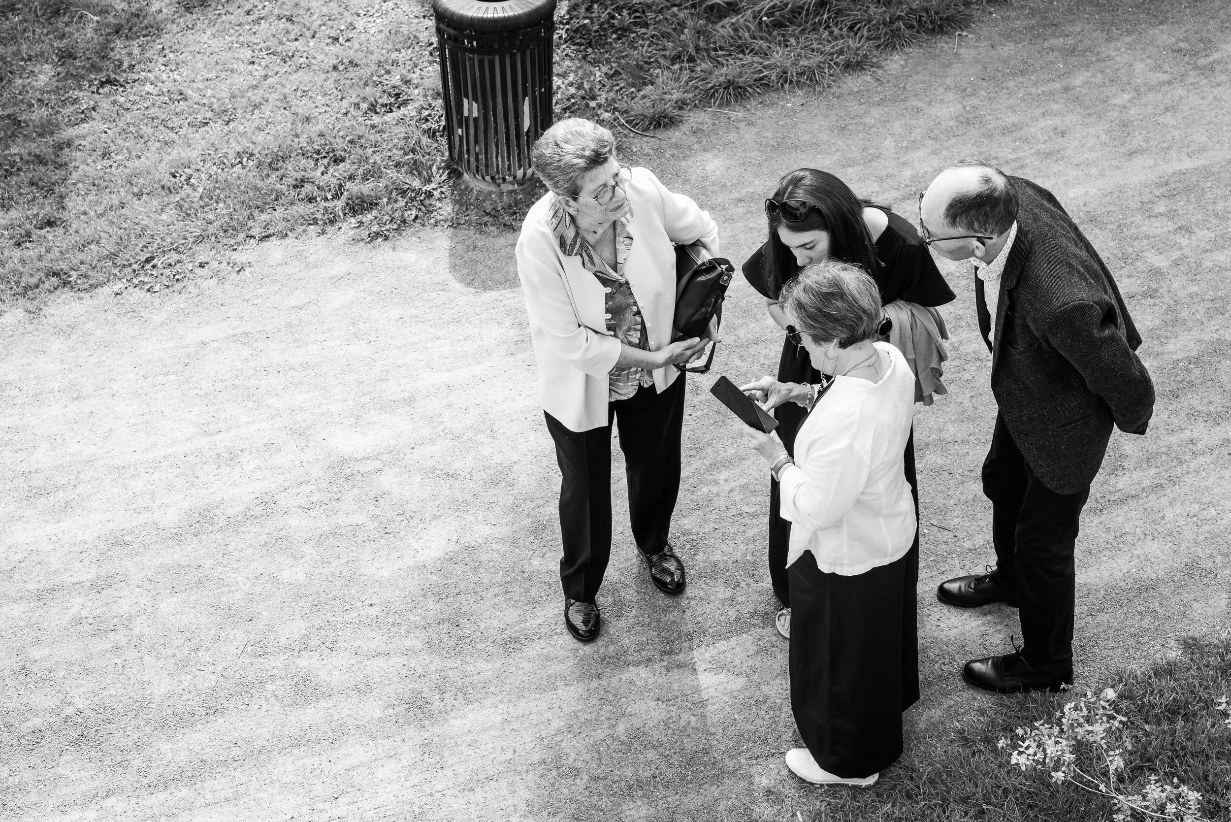 Groupe de quatre personnes debout sur un chemin de gravier, discutant et regardant une tablette numérique.