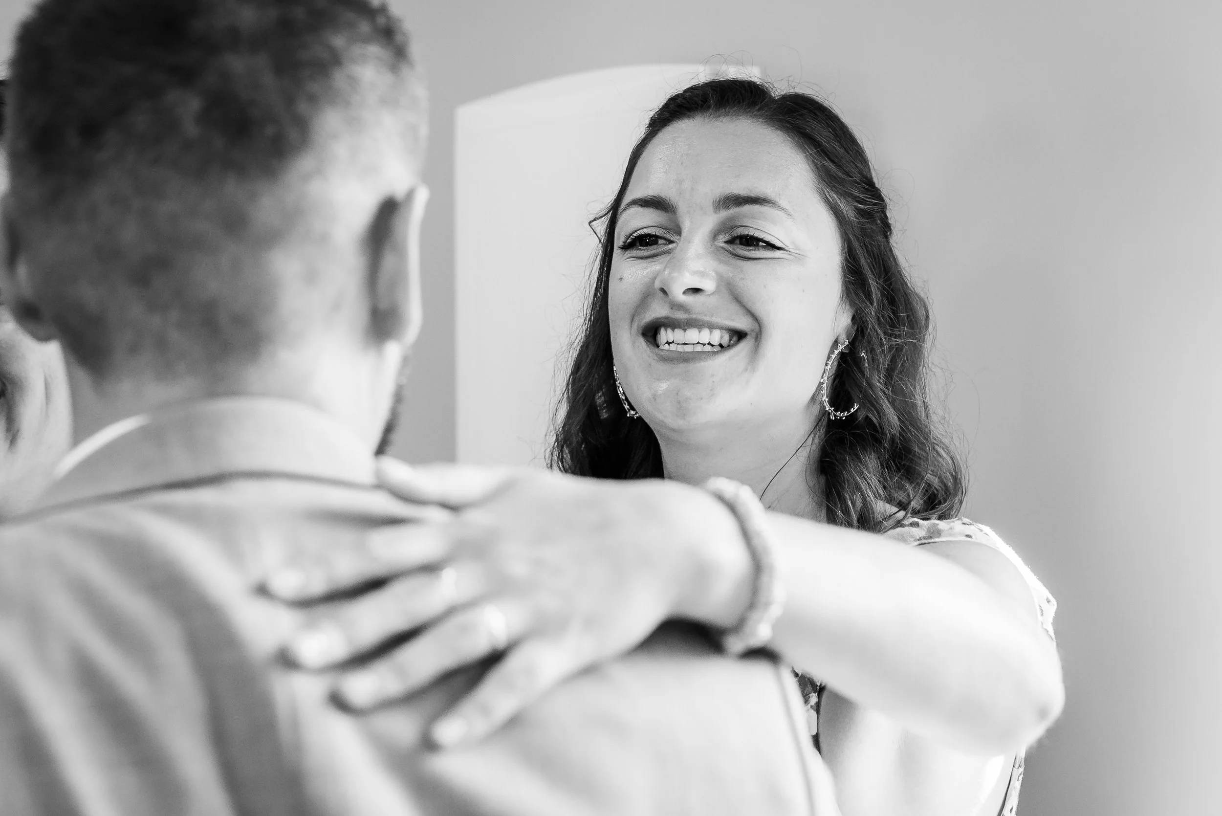 Une femme souriante regarde un homme dans un décor intérieur en noir et blanc.