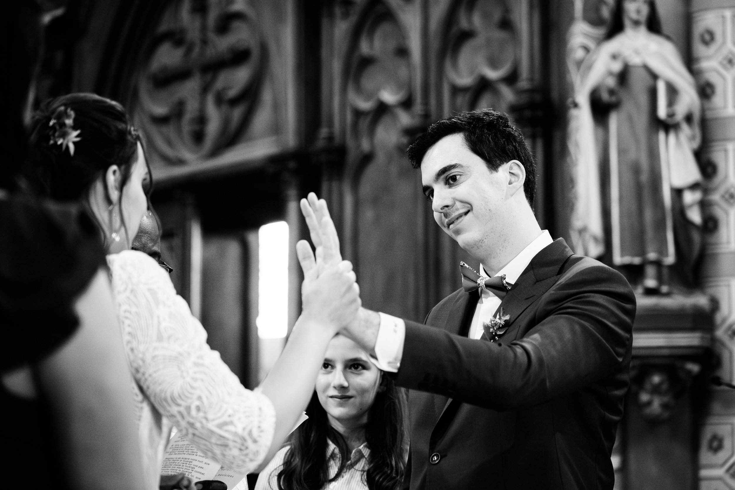 Un homme et une femme s'échangent un vœu lors d'une cérémonie religieuse, probablement un mariage, dans une église.