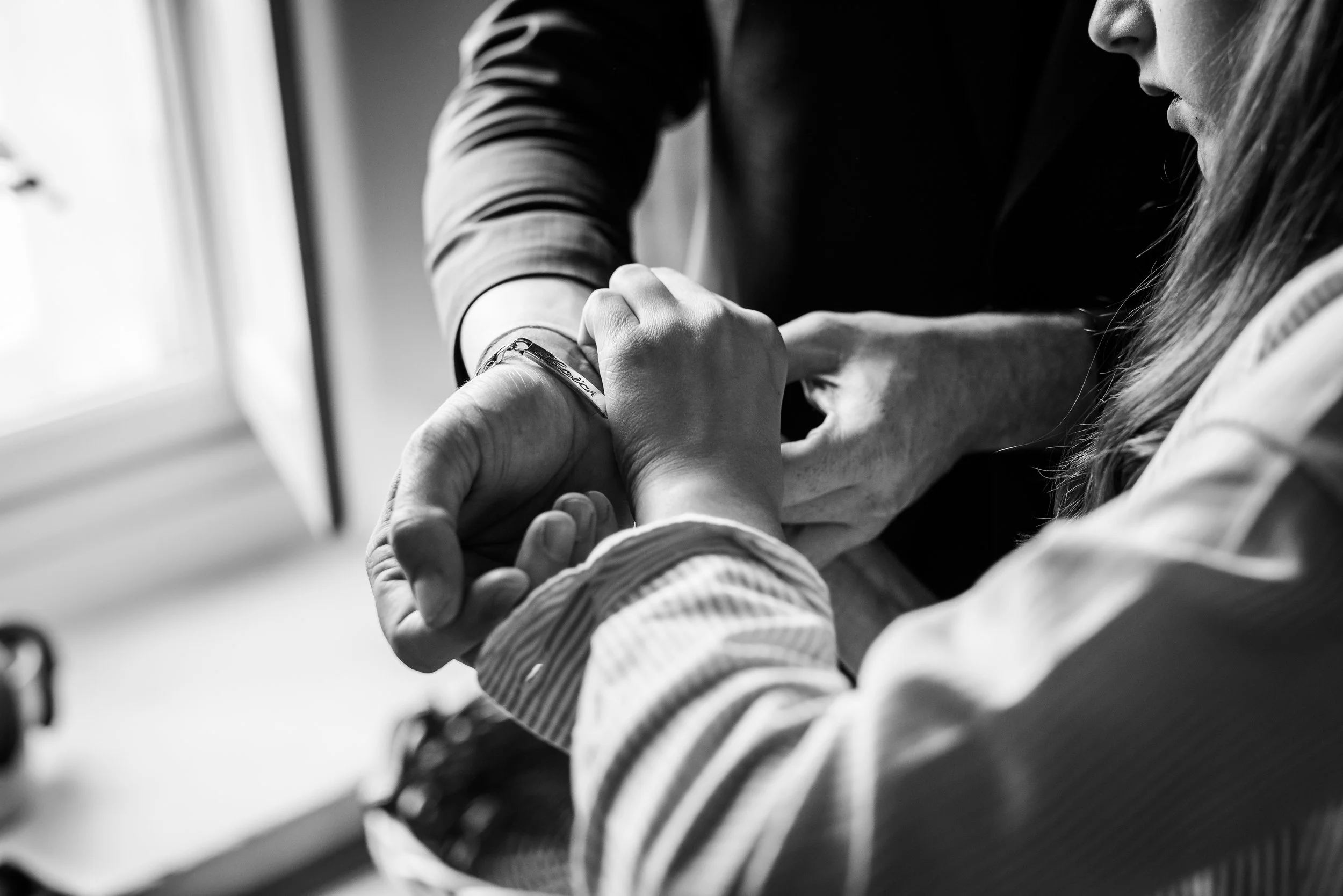 Deux personnes en train d'échanger un contact, une main tenant un bracelet. Photo en noir et blanc, concentrée sur les mains et le visage partiel d'une des personnes.
