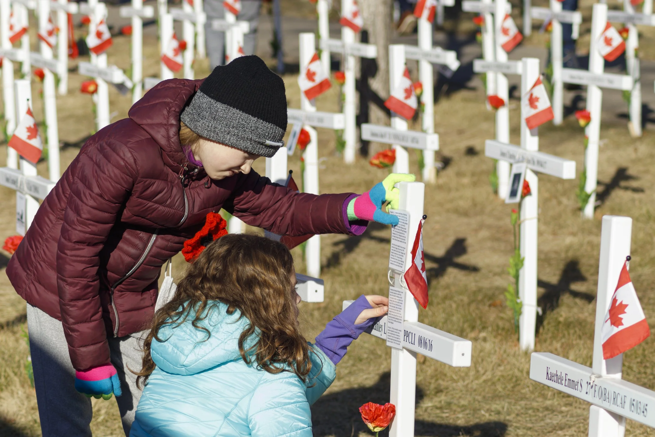 Erica Lea and Bronwyn Pierce are reading a memorial cross at the Field of Crosses on Memorial Drive in Calgary, Alta on Thursday, Nov. 11, 2021. The children were searching for the name “Robert” amongst the crosses.